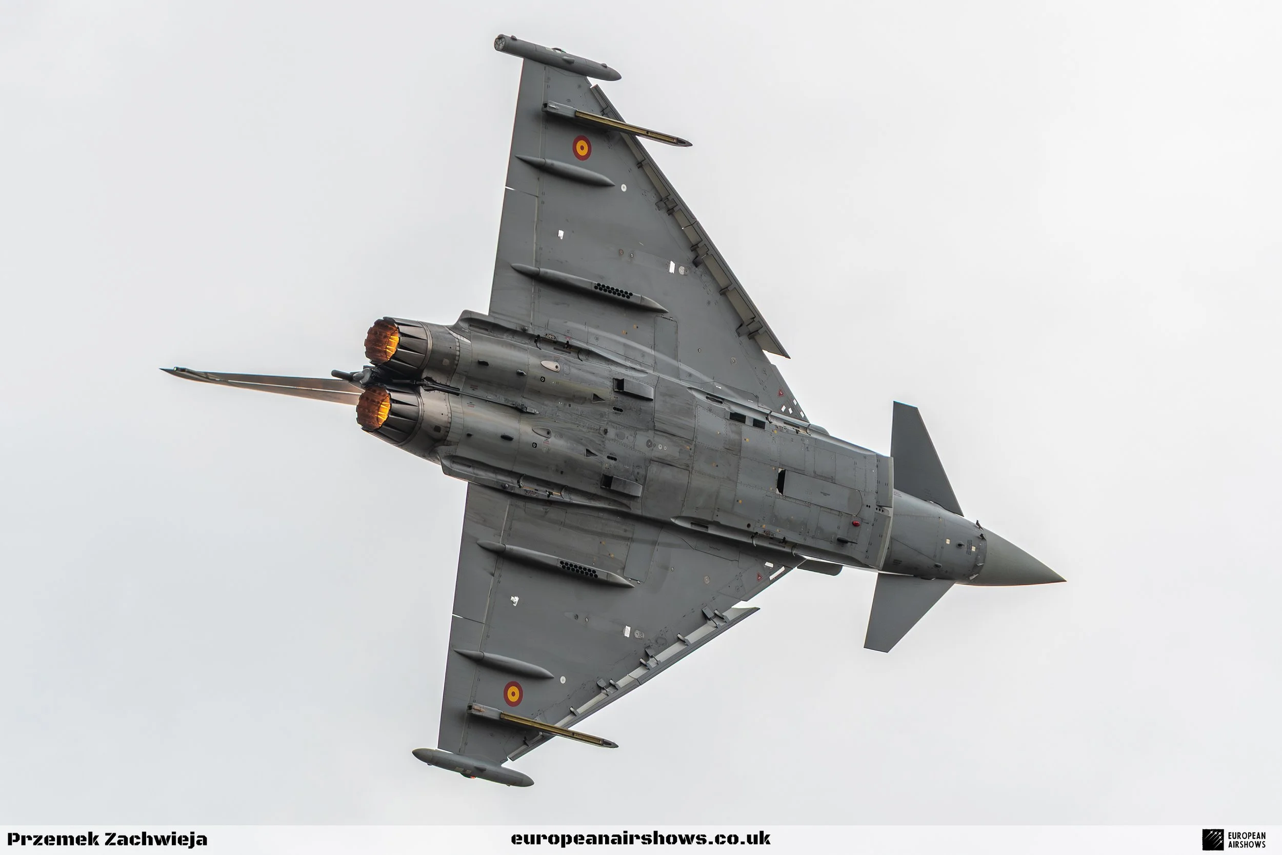 A fighter jet flying through the sky, viewed from below.