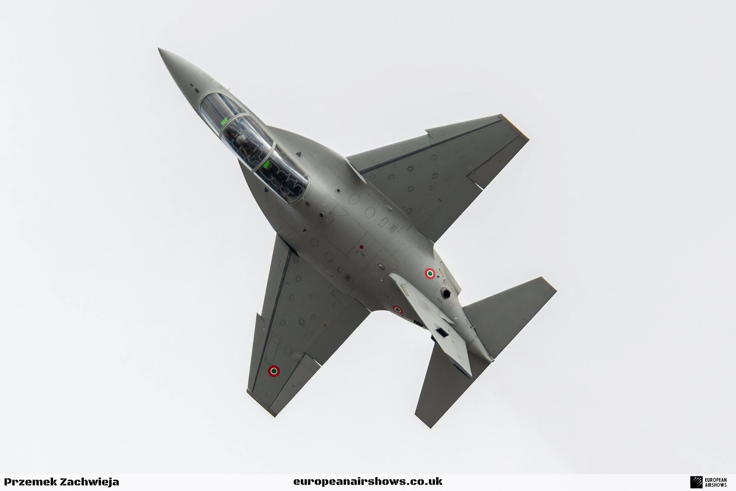 A fighter jet flying in the sky viewed from below.