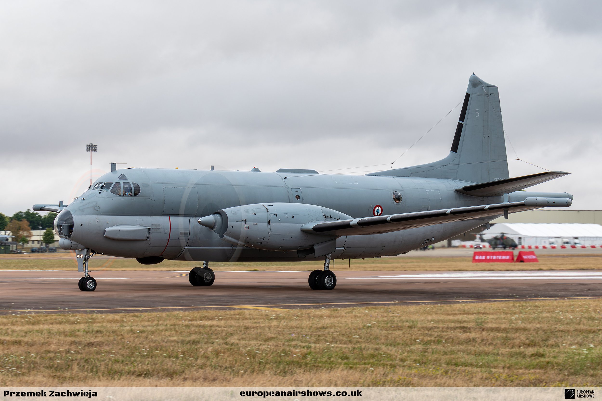 Military aircraft on the runway during an airshow under cloudy sky.