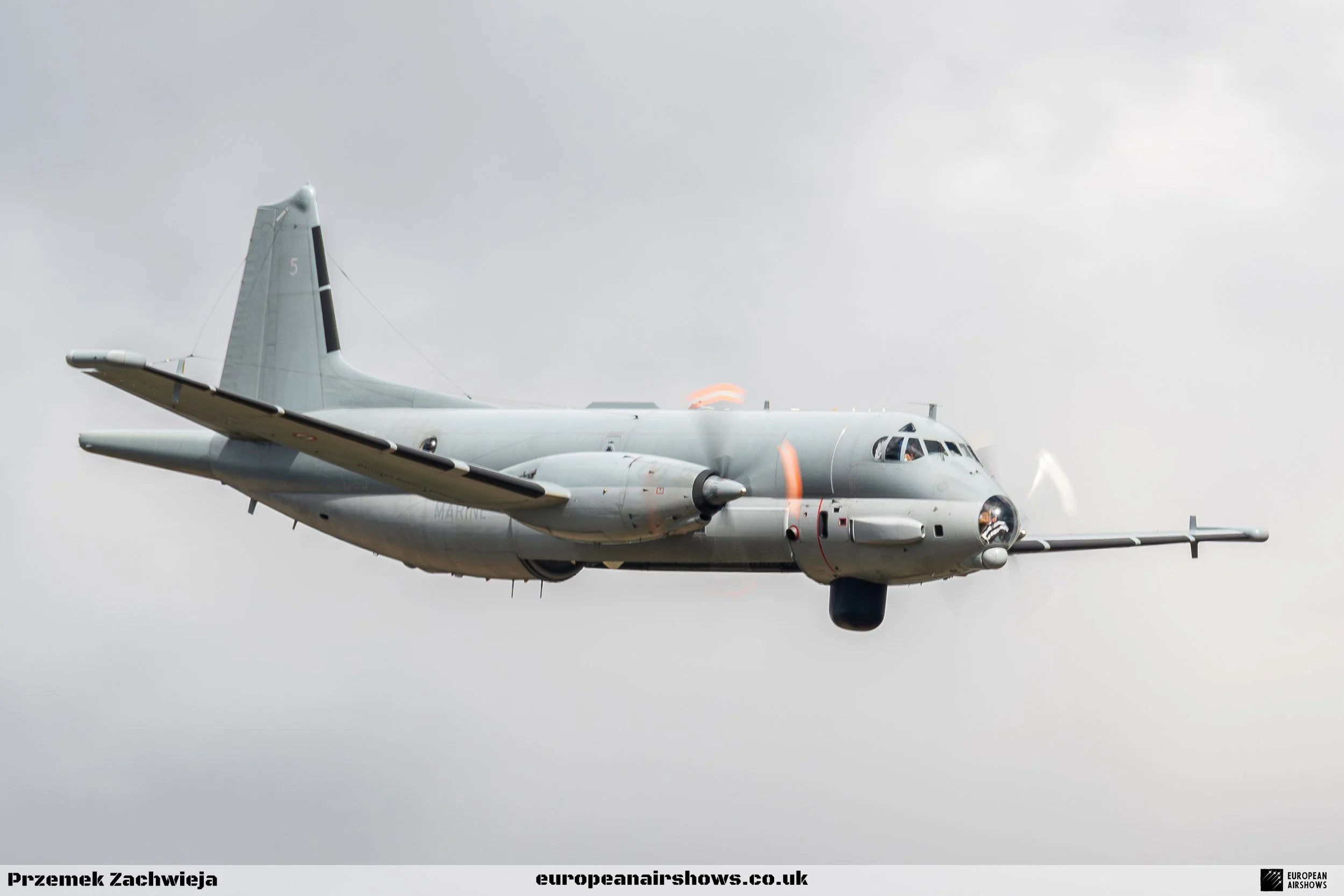 Military aircraft flying in cloudy sky.