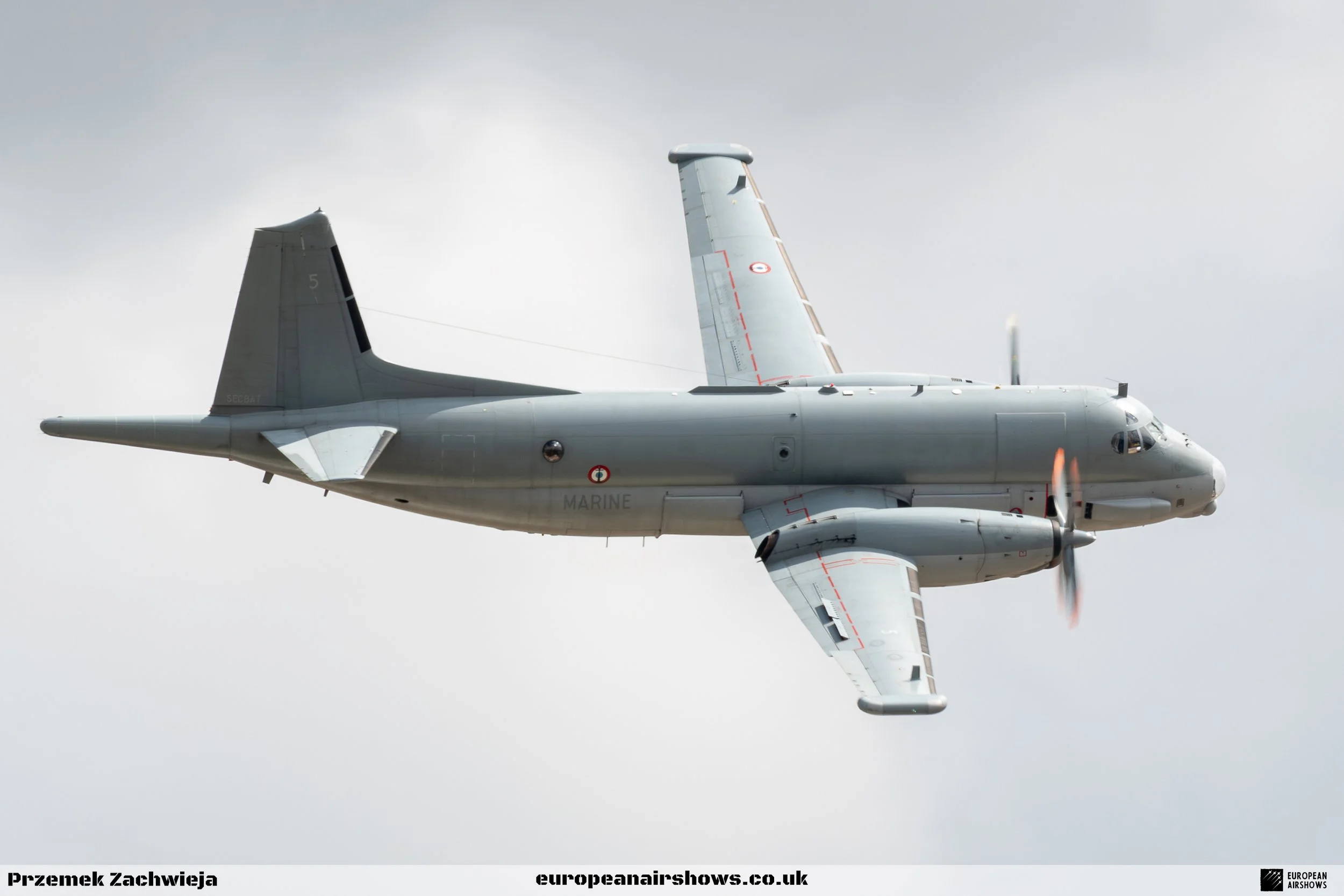 A military aircraft flying in the sky with a cloudy background.