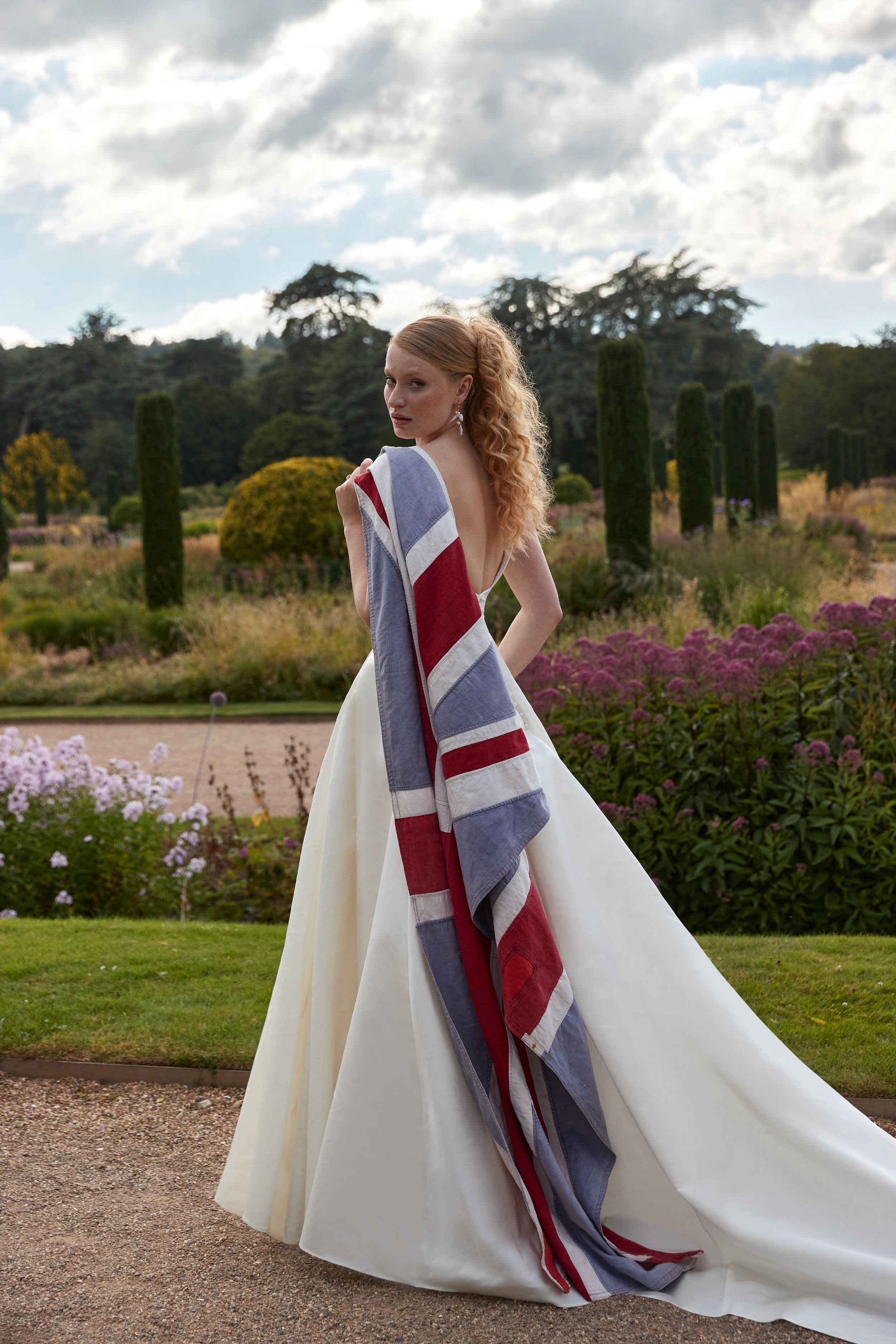 Sassi Holford dress, model carrying a Union Jack flag draped over her shoulder.  Great British design available at Boo Bridal