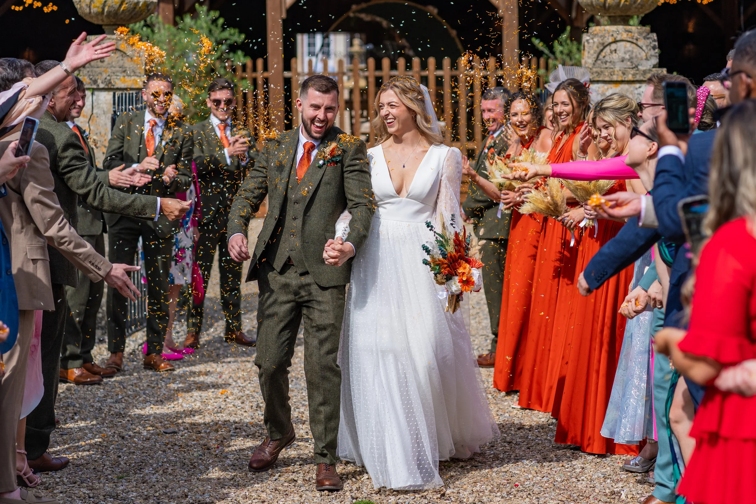 Bride and groom confetti shot.  bride wears a Sassi Holford gown from Boo Bridal, bridesmaids are in orange