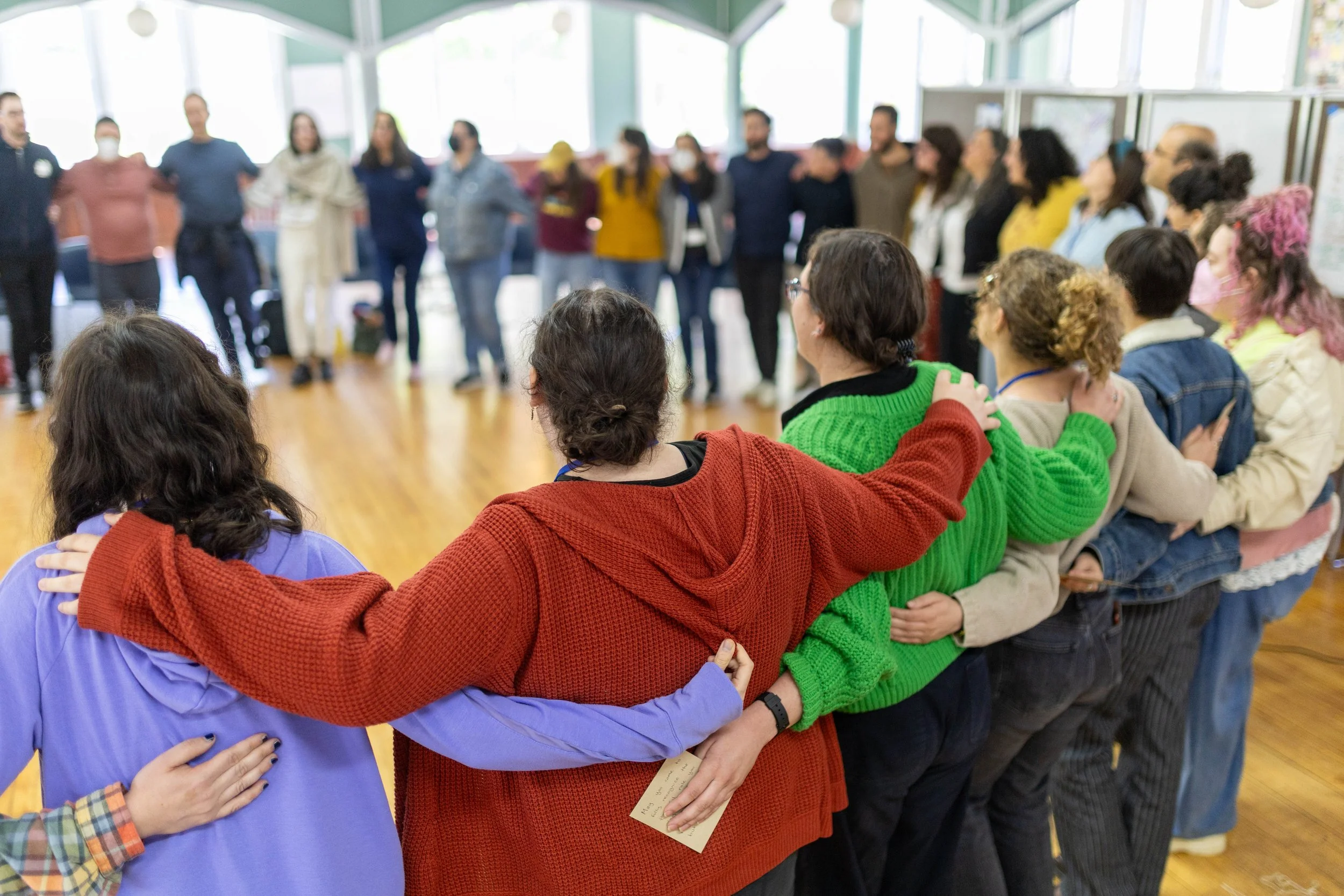 organizers from across the Collaborative stand in a circle with their arms around each other at the Spring 2026 organizer convening. 