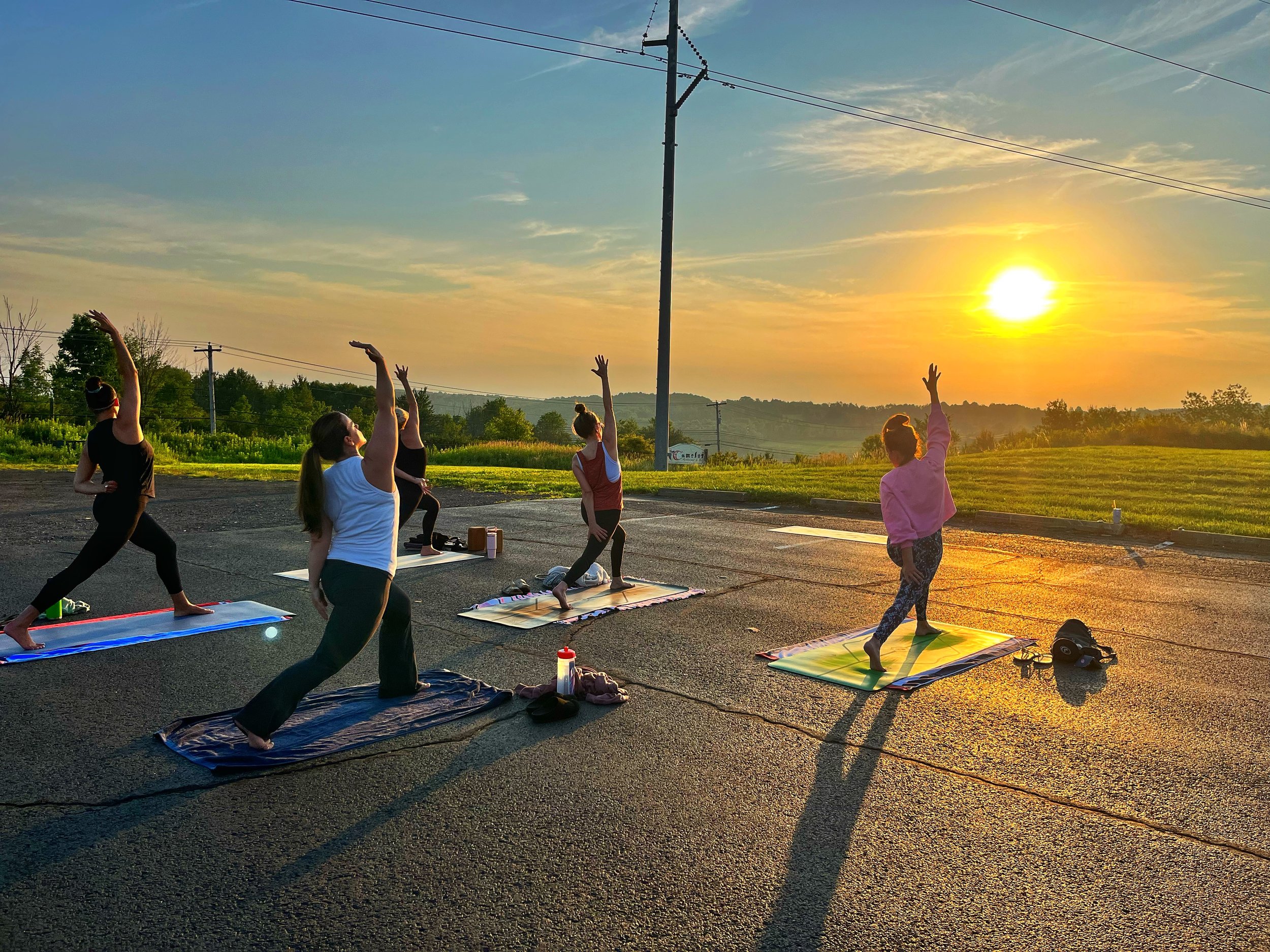 People practicing a lunging side stretch at Camelot Restaurant & Inn during a yoga class led by Jaya Yoga Studio in Clarks Summit, Pennsylvania.