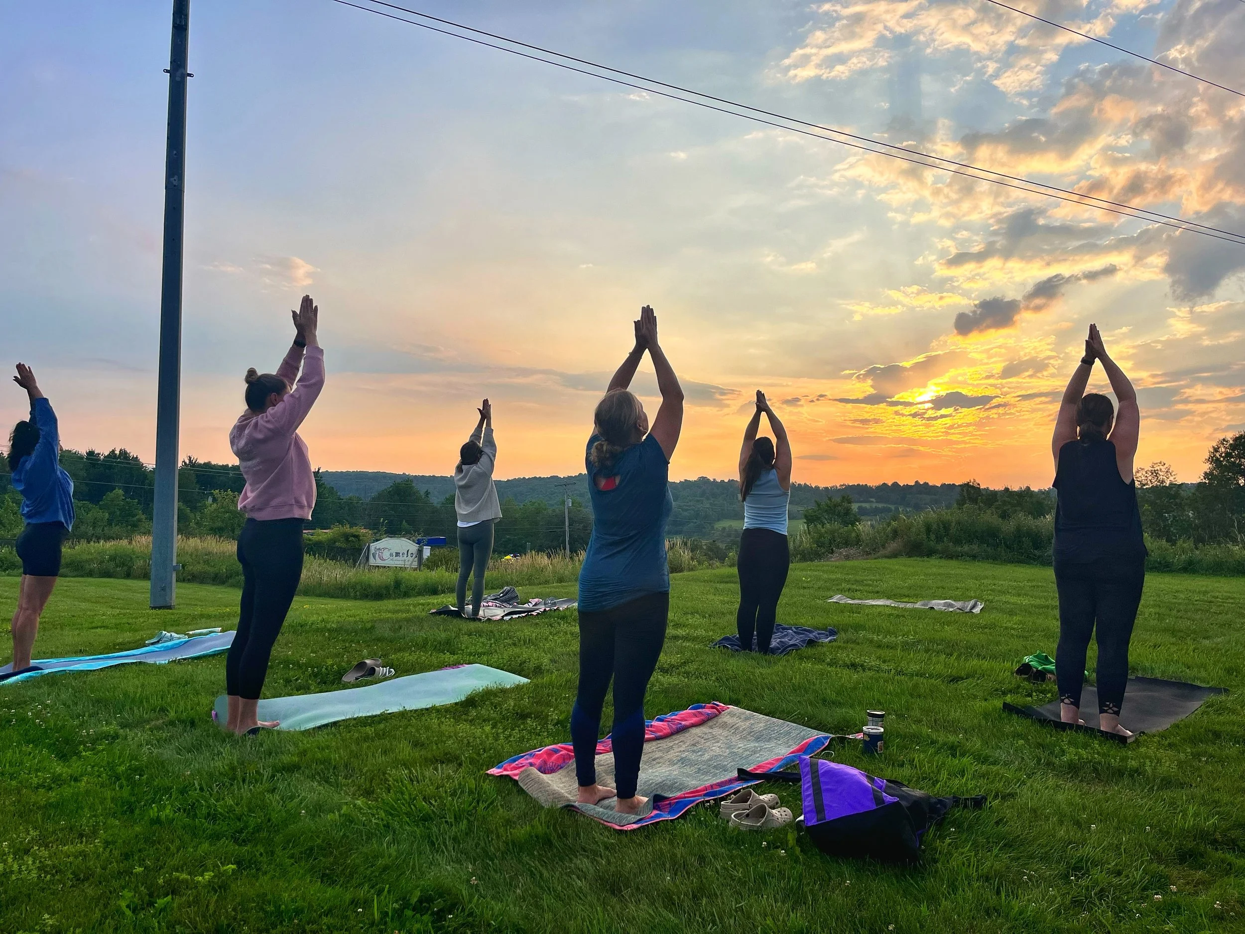 People reaching their arms to the sky during a sunrise yoga class at Camelot Restaurant & Inn, led by Jaya Yoga Studio in Clarks Summit, Pennsylvania.