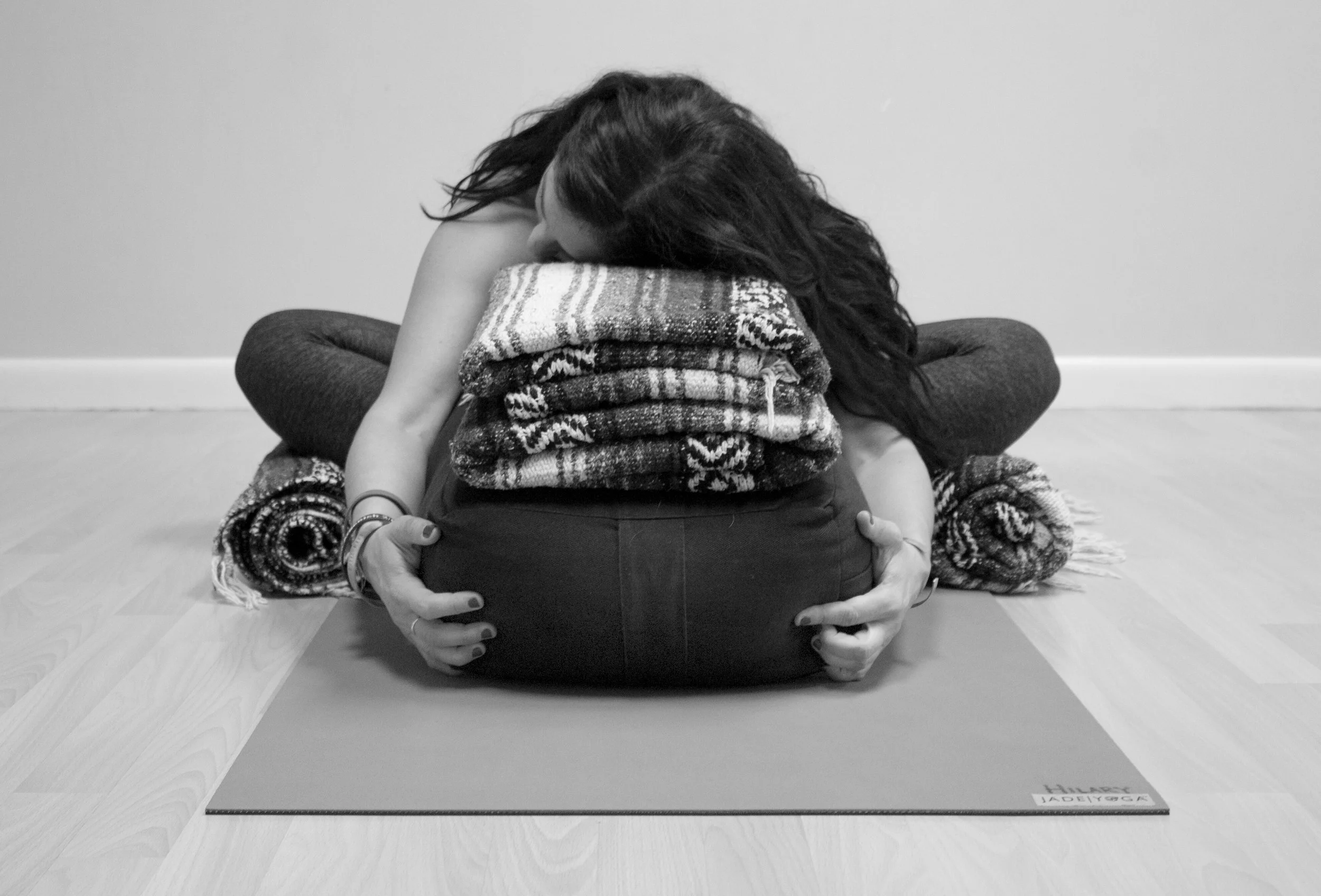 Person in supported bound angle pose (Supta Baddha Konasana) on a yoga mat, practicing restorative yoga for relaxation and stress relief.