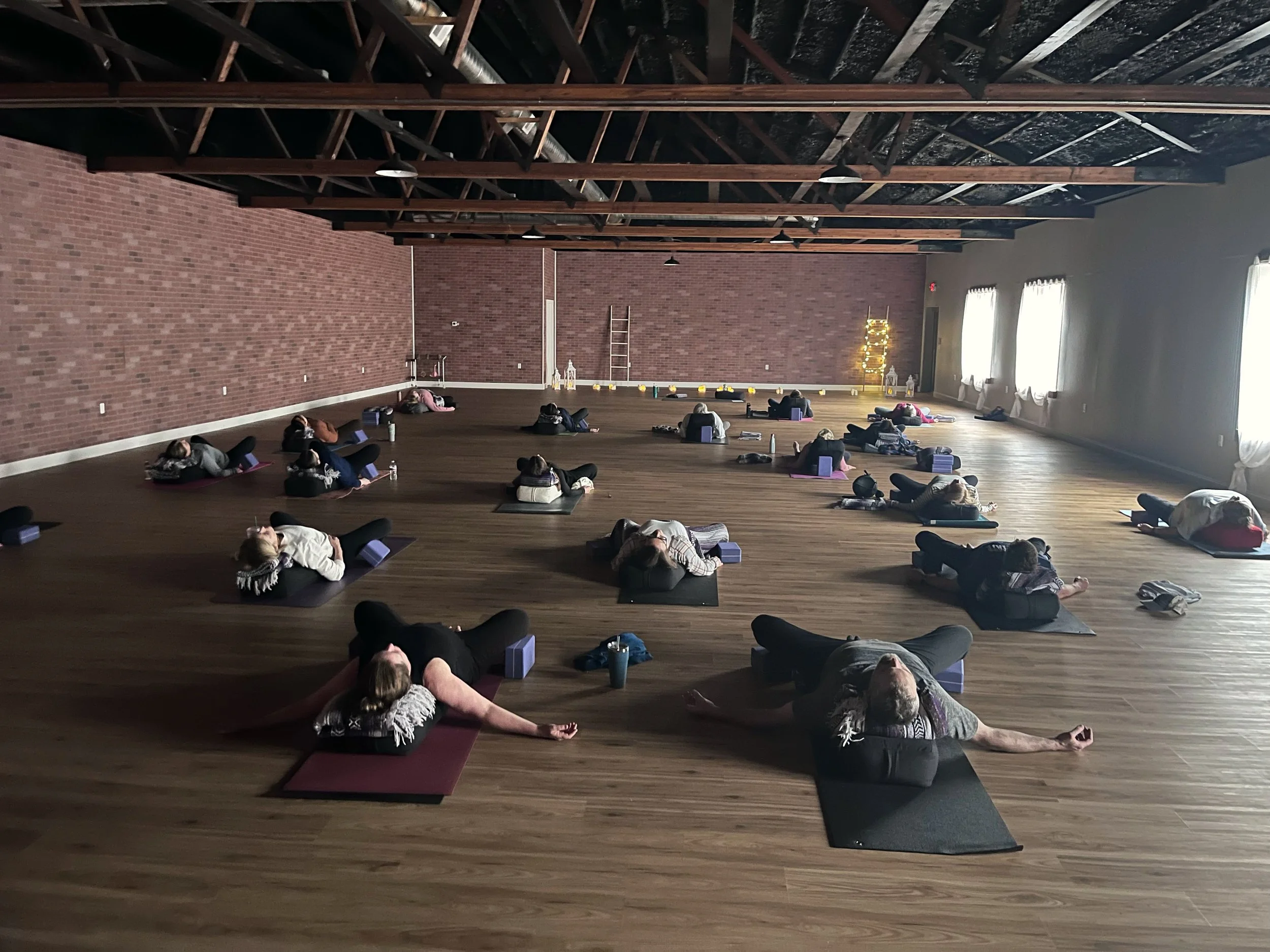 Students resting in fully supported poses with bolsters during a restorative yoga class at Jaya Yoga Studio in Clarks Summit, PA.