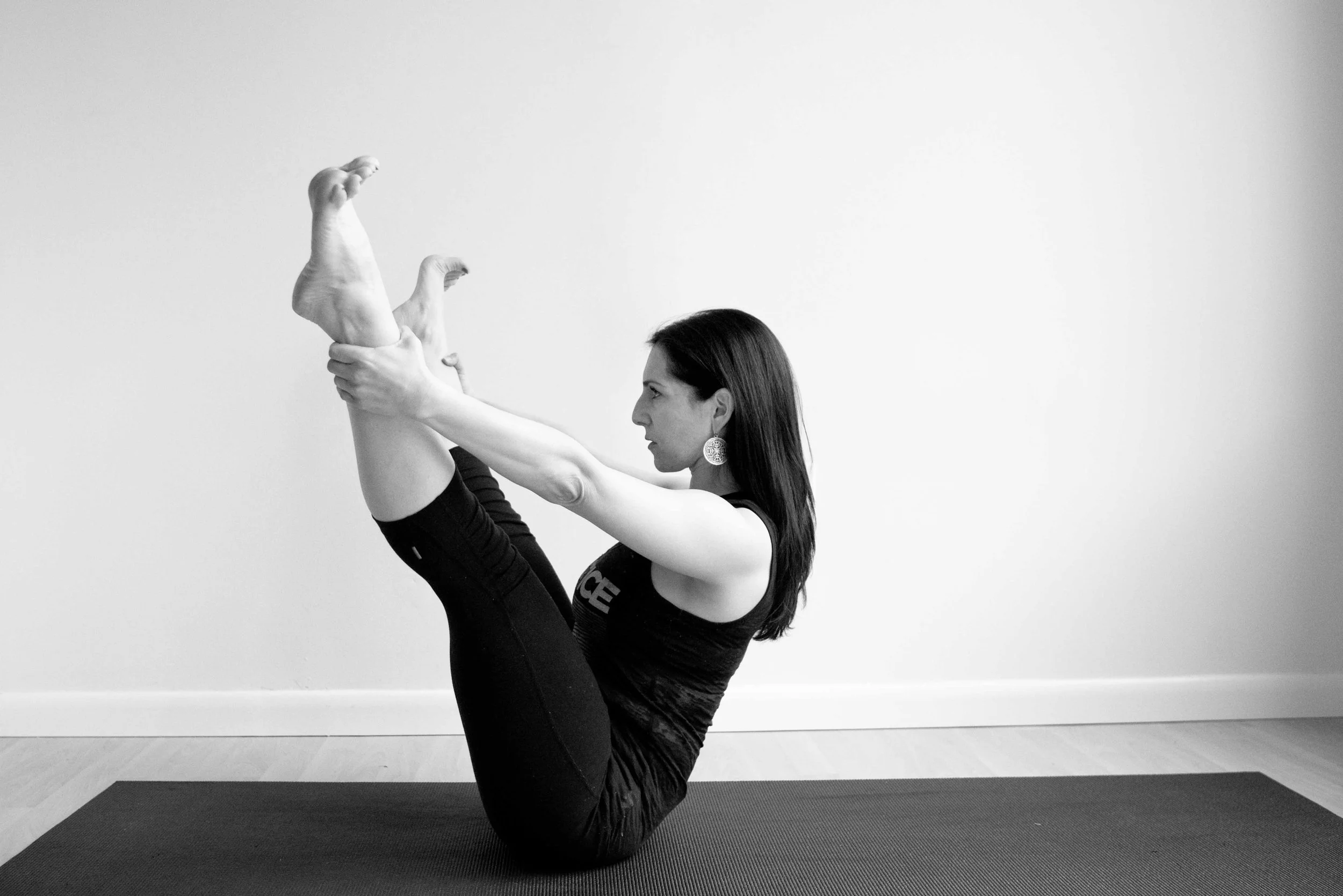 Instructor at Jaya Yoga Studio performing the Open Leg Rocker exercise during a mat Pilates practice in Clarks Summit, PA.