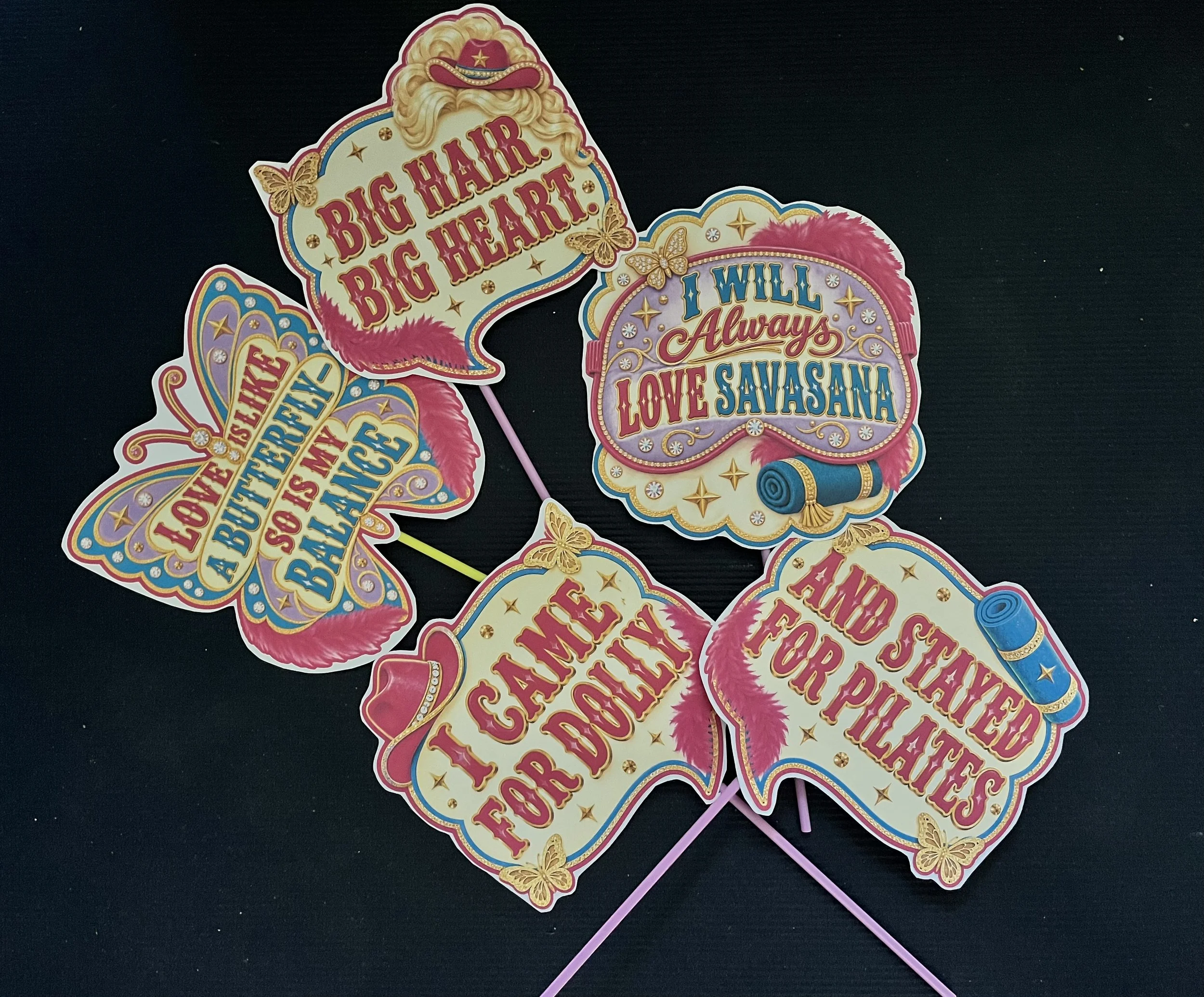 Five colorful Dolly-inspired photo booth signs for Jaya Yoga Studio’s Dolly Parton Day celebration, including “Big Hair, Big Heart” and “I Will Always Love Savasana.”
