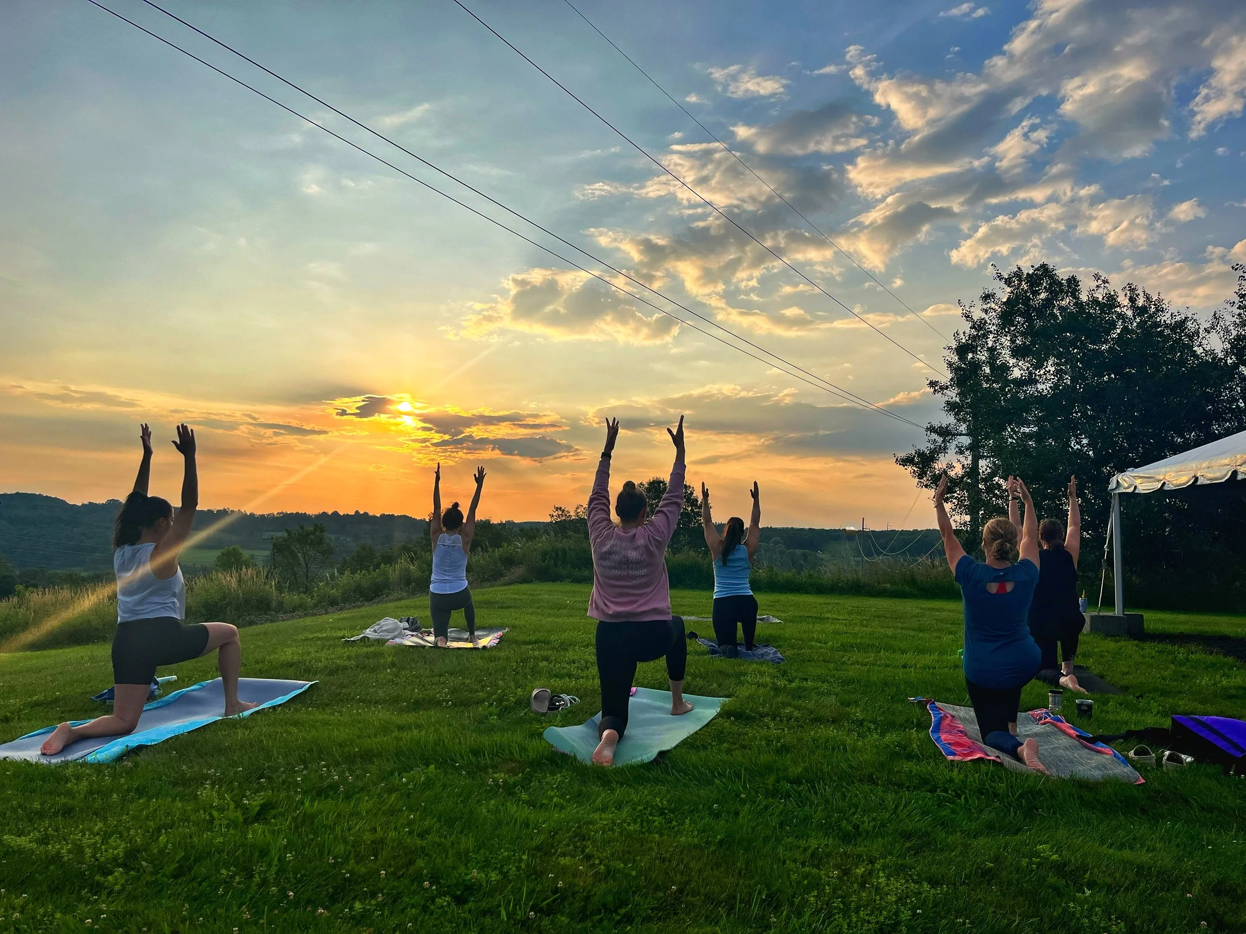 People practicing low lunge pose during a sunrise yoga class at Camelot Restaurant & Inn, led by Jaya Yoga Studio in Clarks Summit, Pennsylvania.