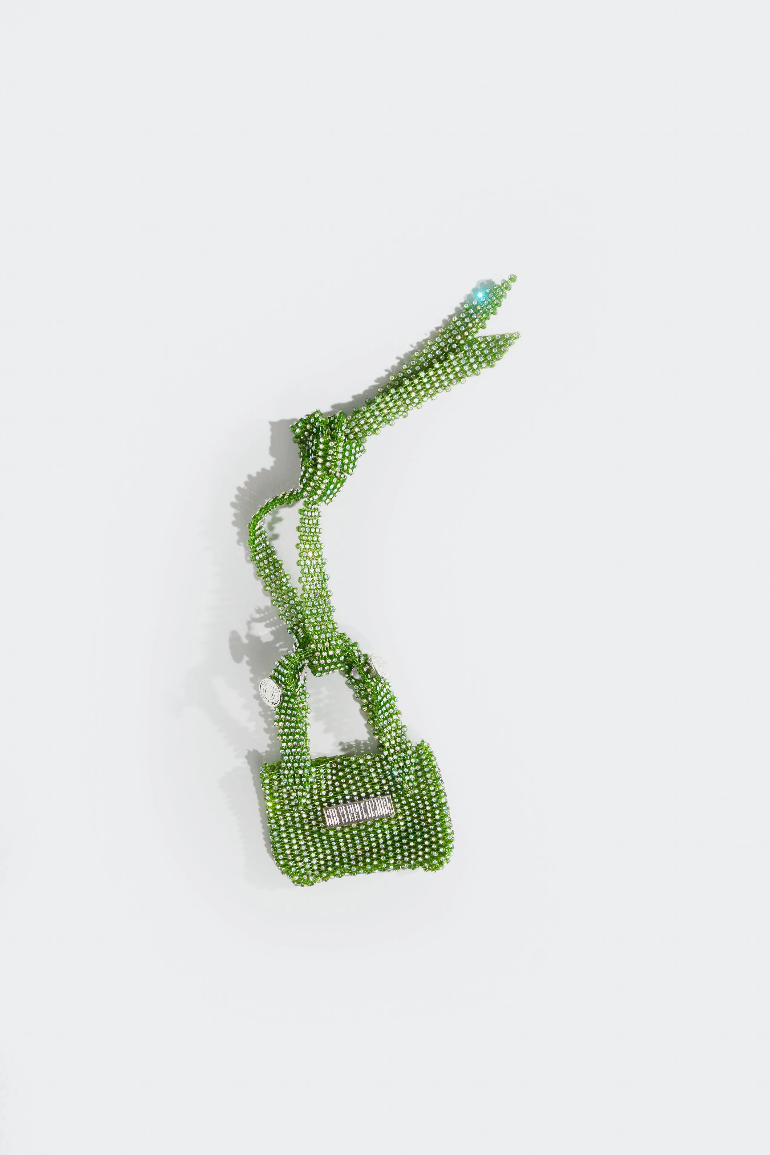 A small handbag and strap decorated with green rhinestones  set against a white background.