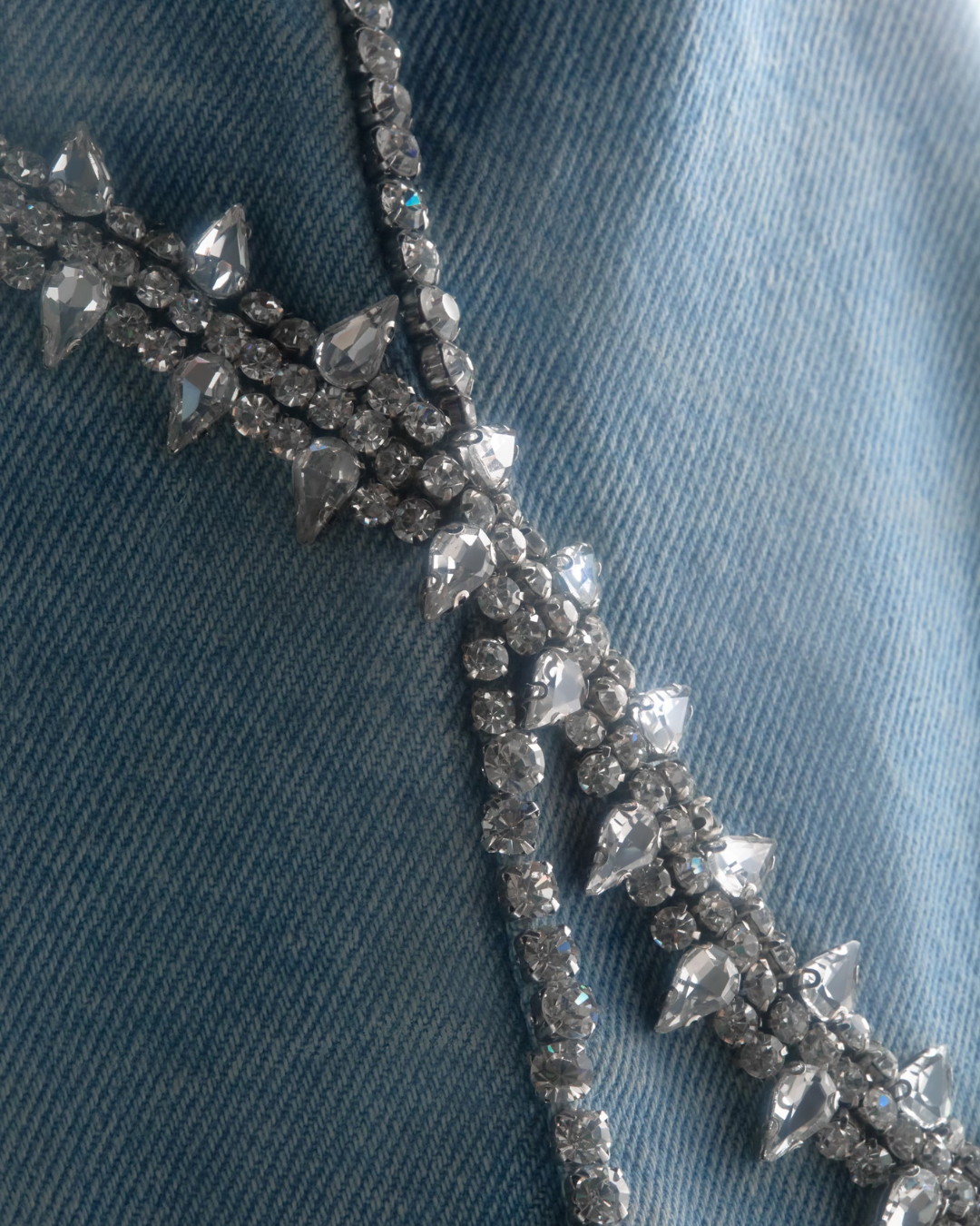 Macro shot of intersecting crystal patterns forming an “X,” showcasing layered beading and light-catching structure.