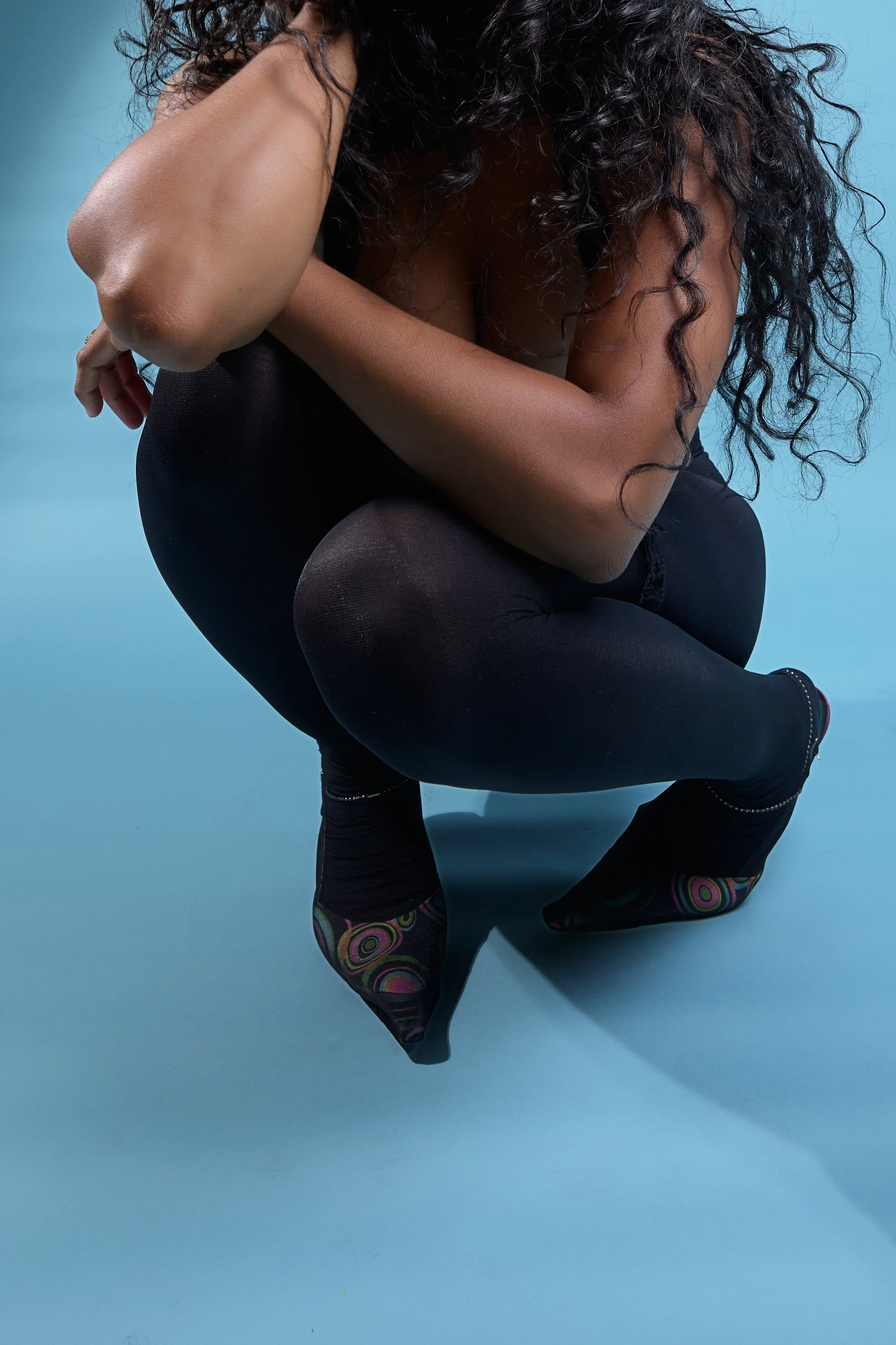 three-quarter pose of cheyennekimora kneeling, arms and legs forming sculptural shapes, face out of frame