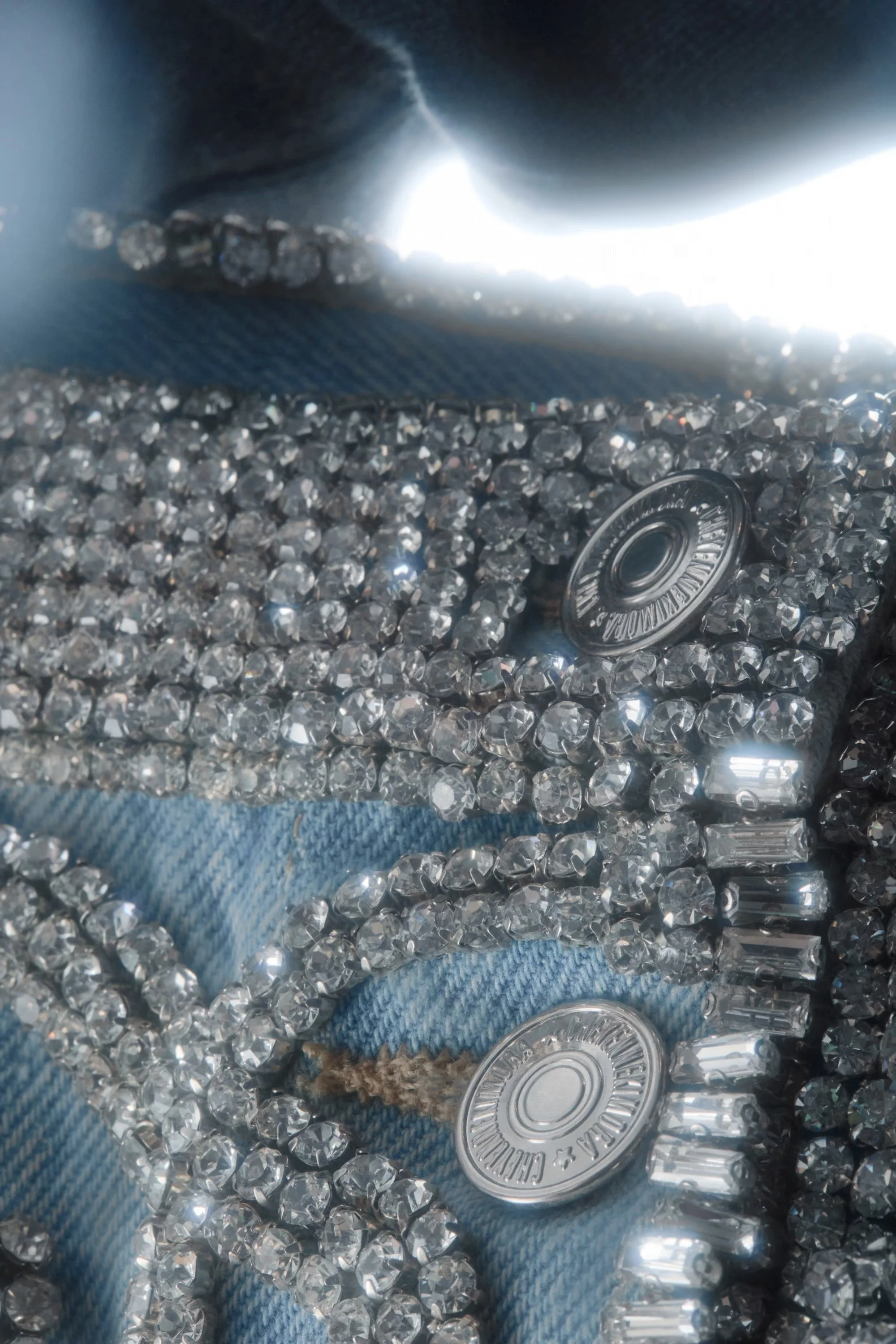 Macro detail of the skirt’s metal button surrounded by hand-applied crystal beading.