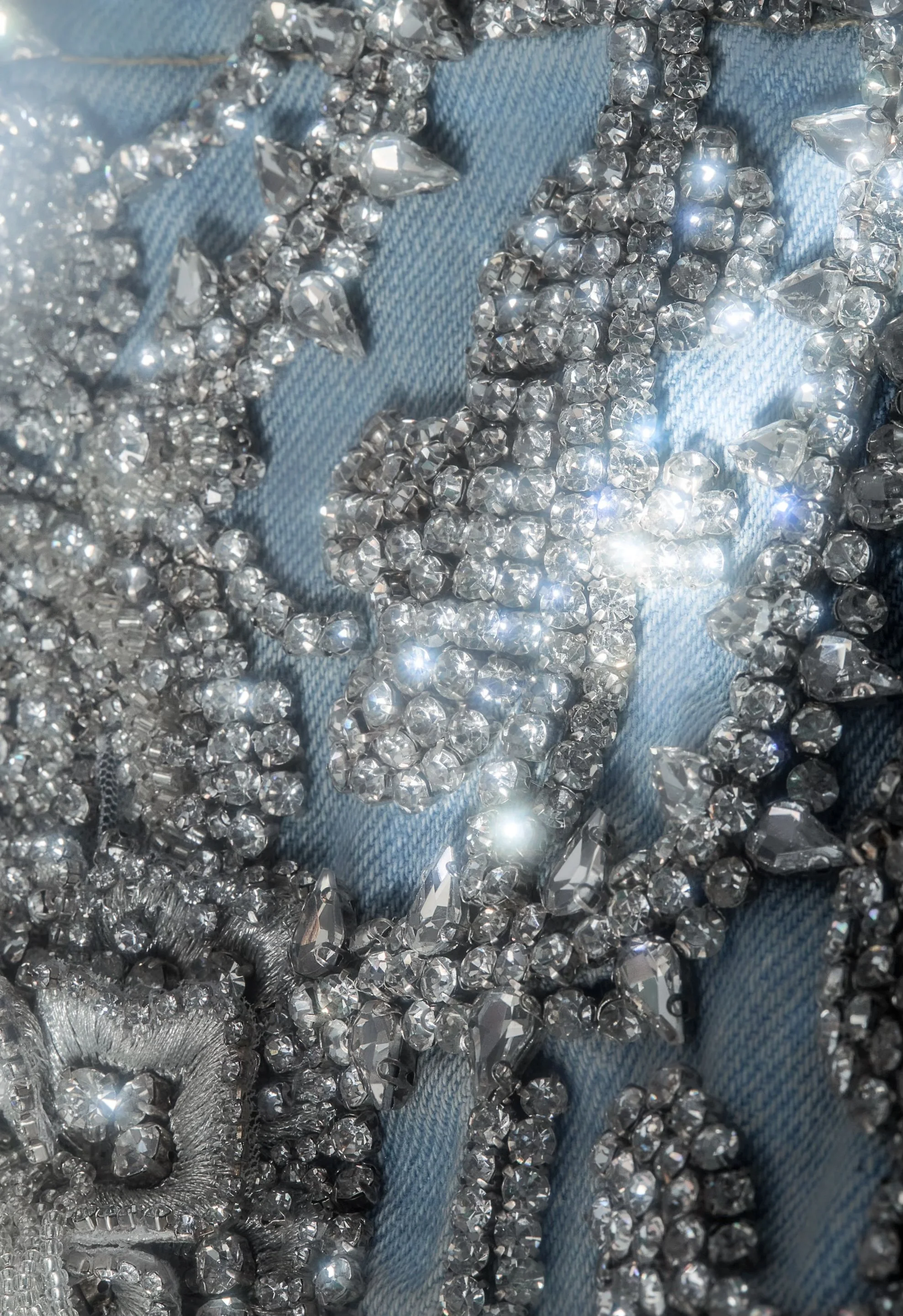 Close-up of hand-applied crystals on denim, revealing intricate beadwork and light-catching texture.