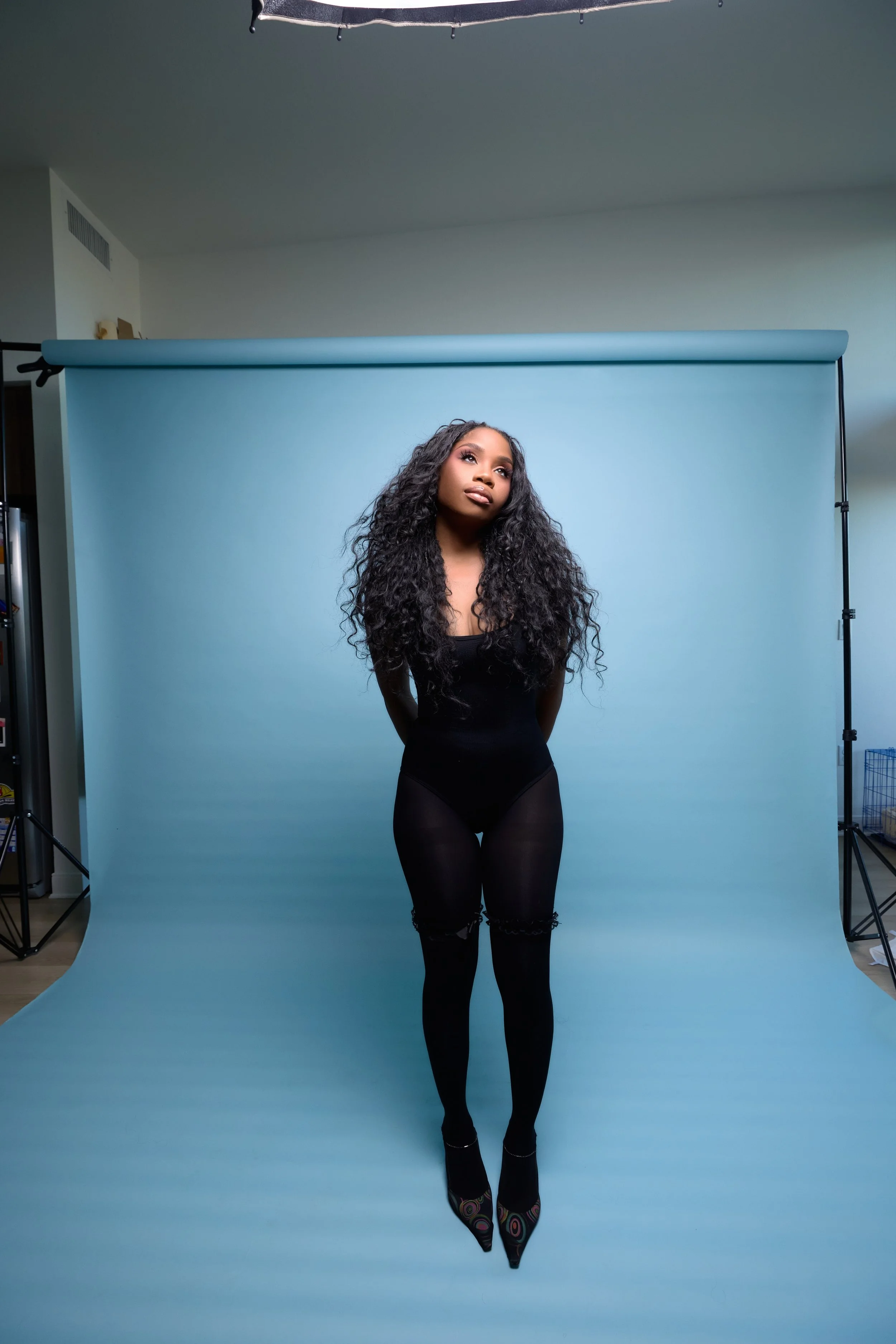 full-body standing shot of cheyennekimora looking upward toward light with arms behind the back