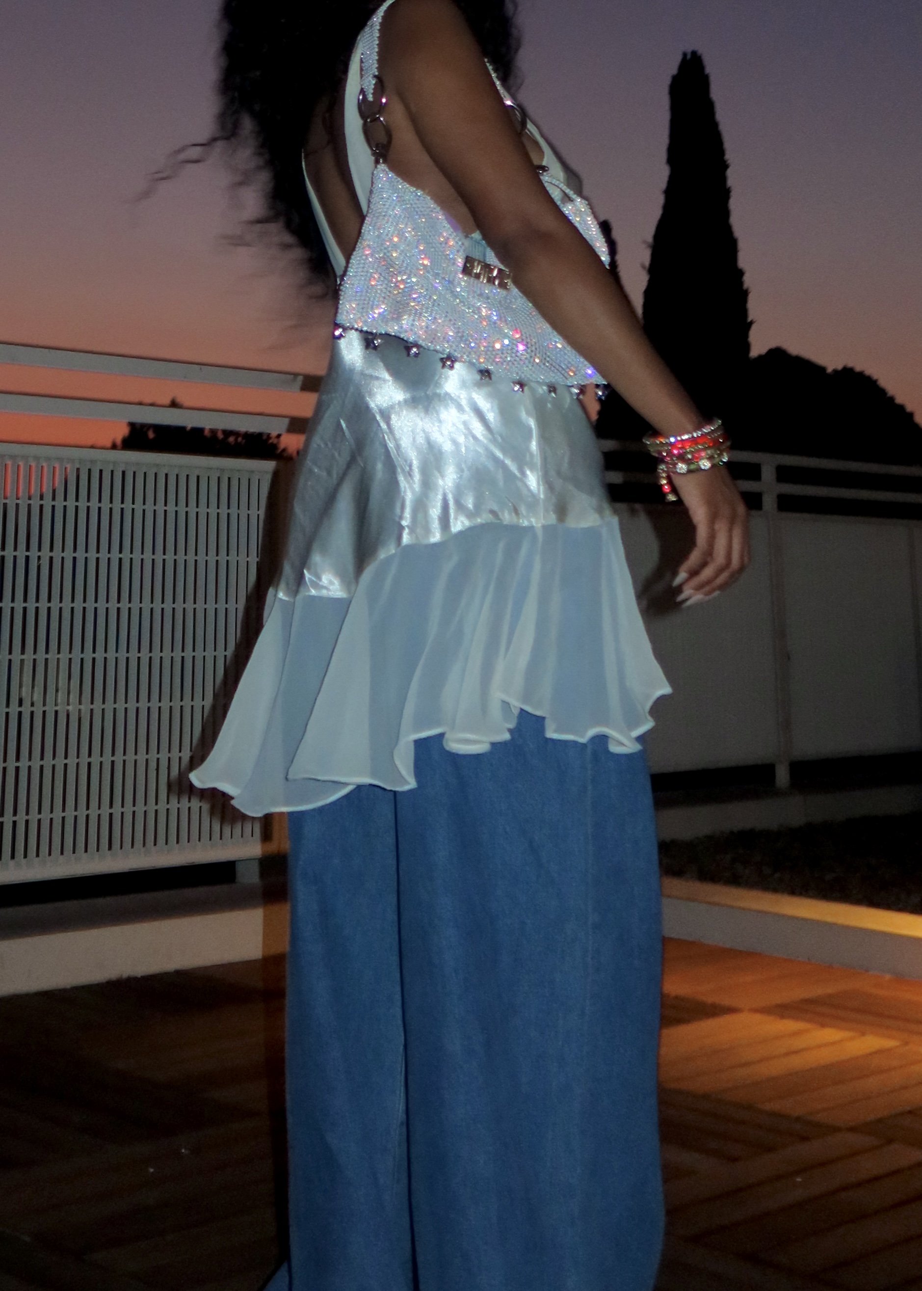 Side-profile view of the Baguette Bag worn under the arm, highlighting its soft drape, crystal details, and elongated strap.