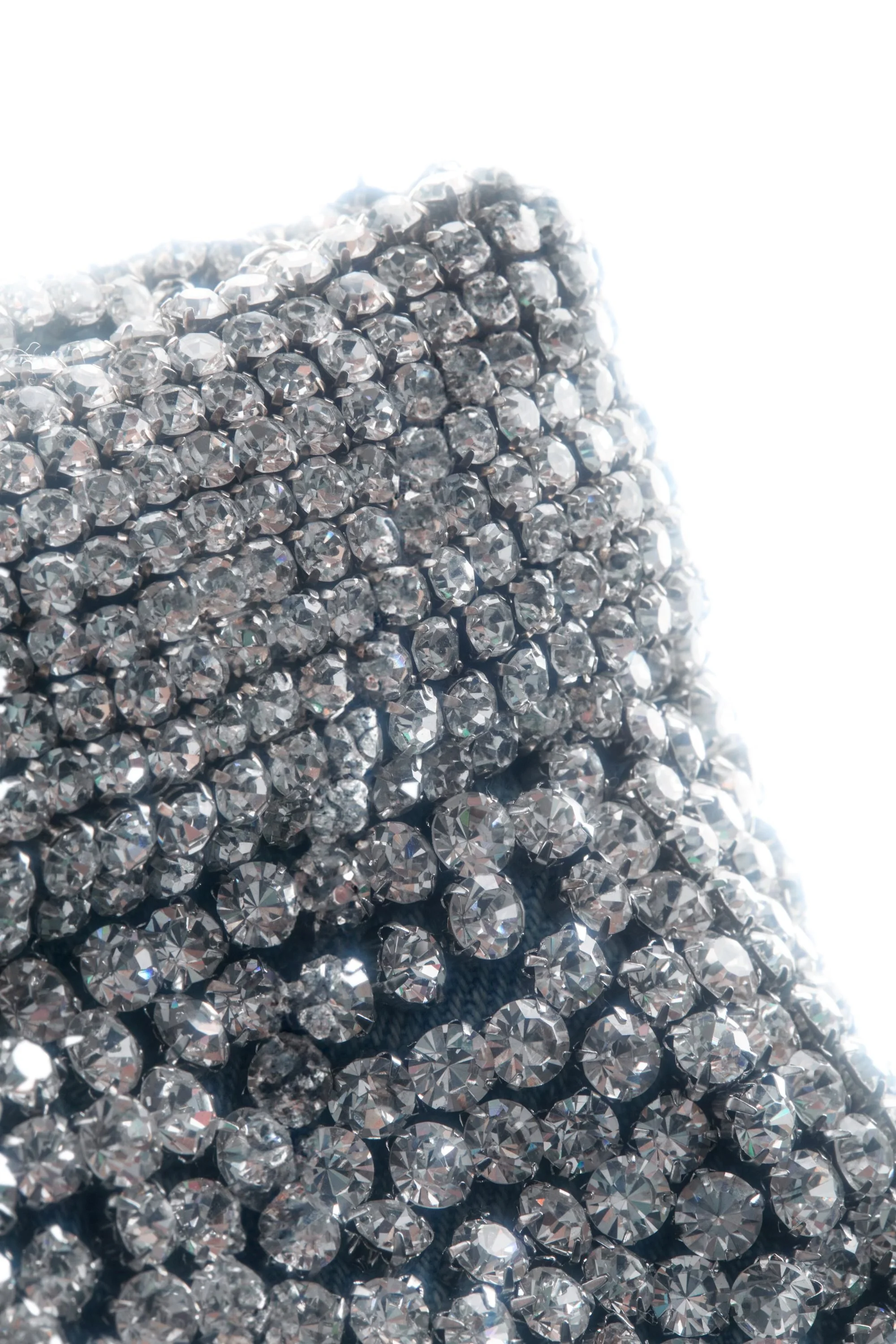 Macro shot of the crystalized mini skirt waistband, showing hand-beaded detailing along the sculpted denim edge.