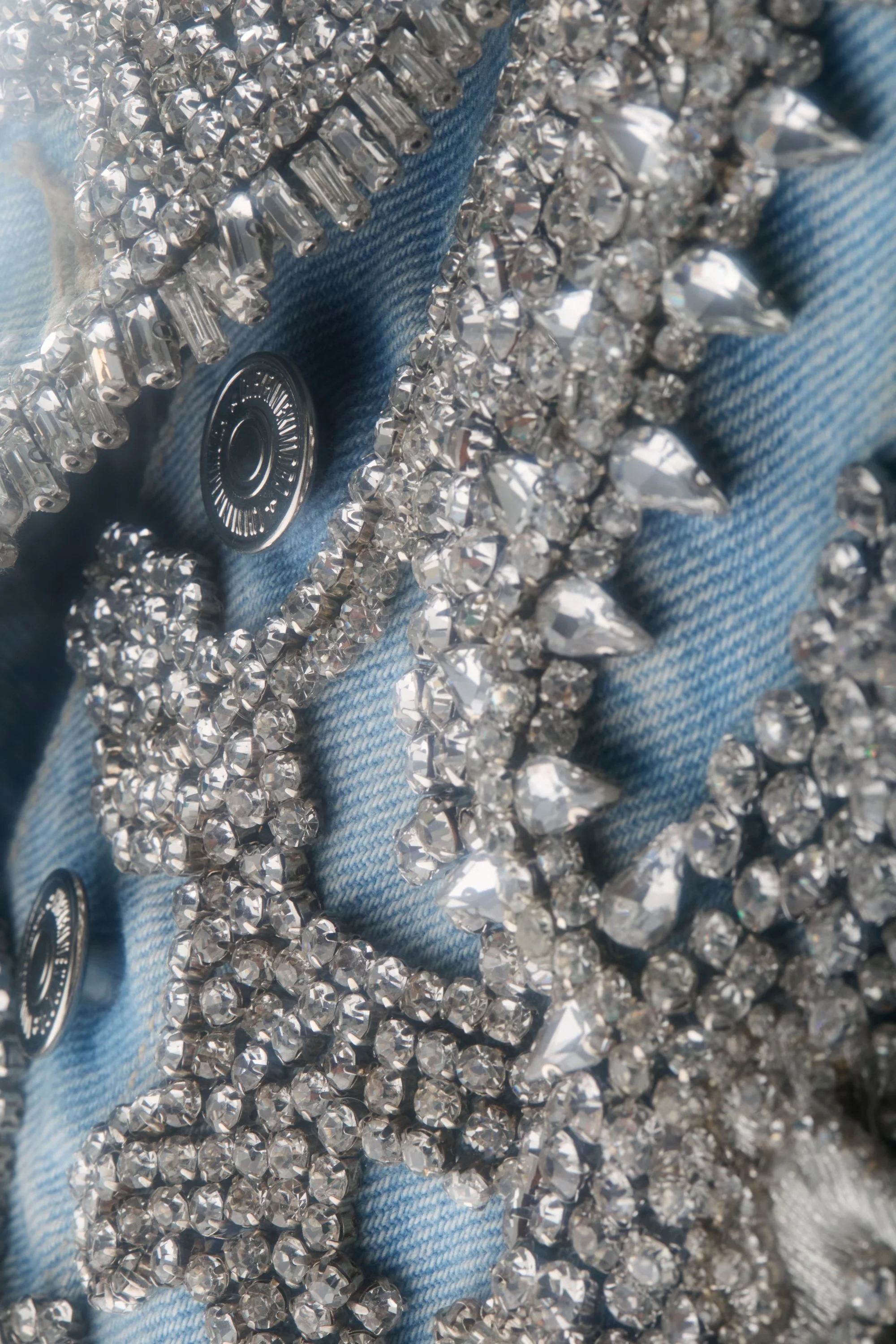 Macro shot of the crystalized mini skirt waistband, showing hand-beaded detailing along the sculpted denim edge.