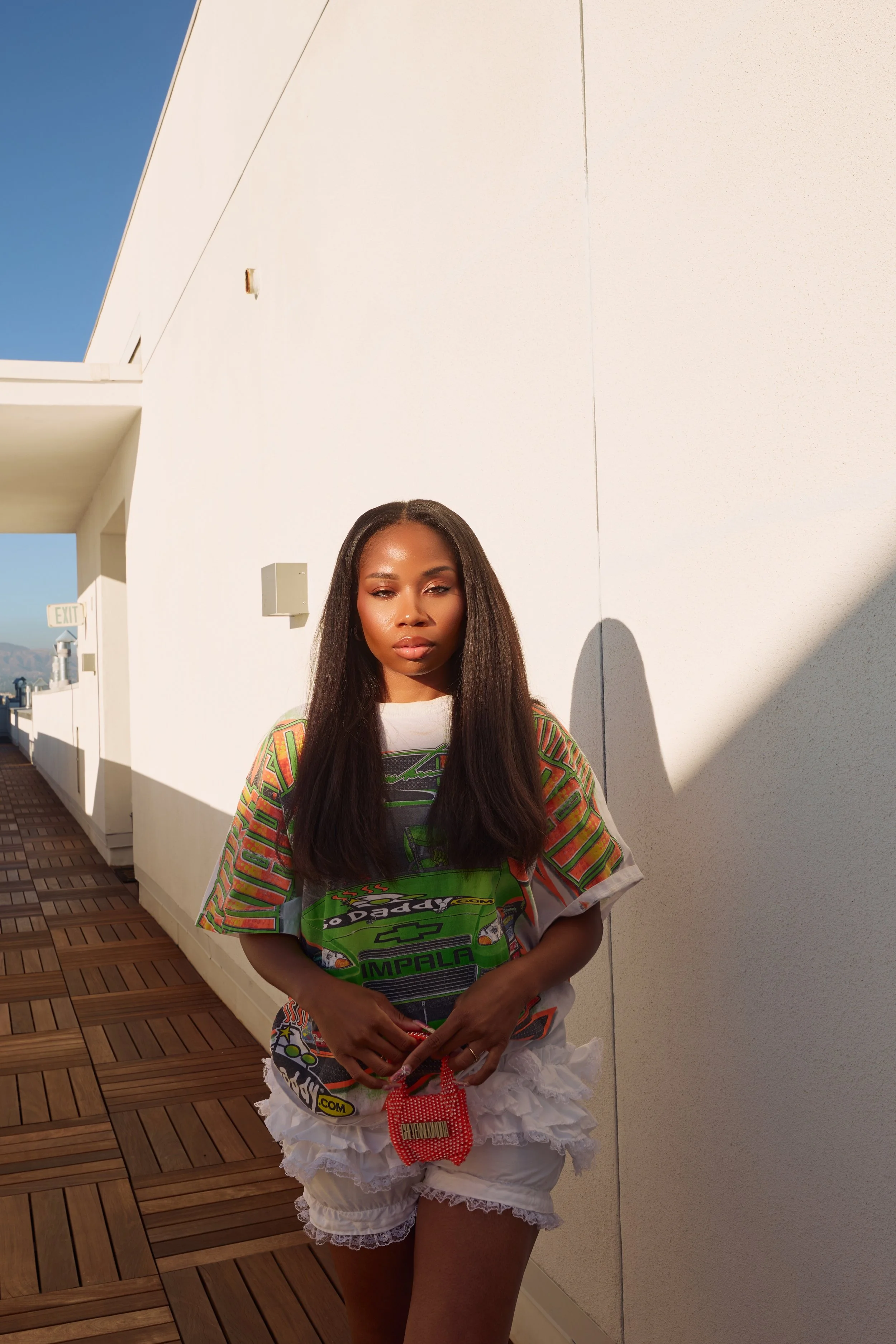 Three-quarter portrait of model holding the Cheyennekimora orange mini bag at her waist, looking directly into the camera..