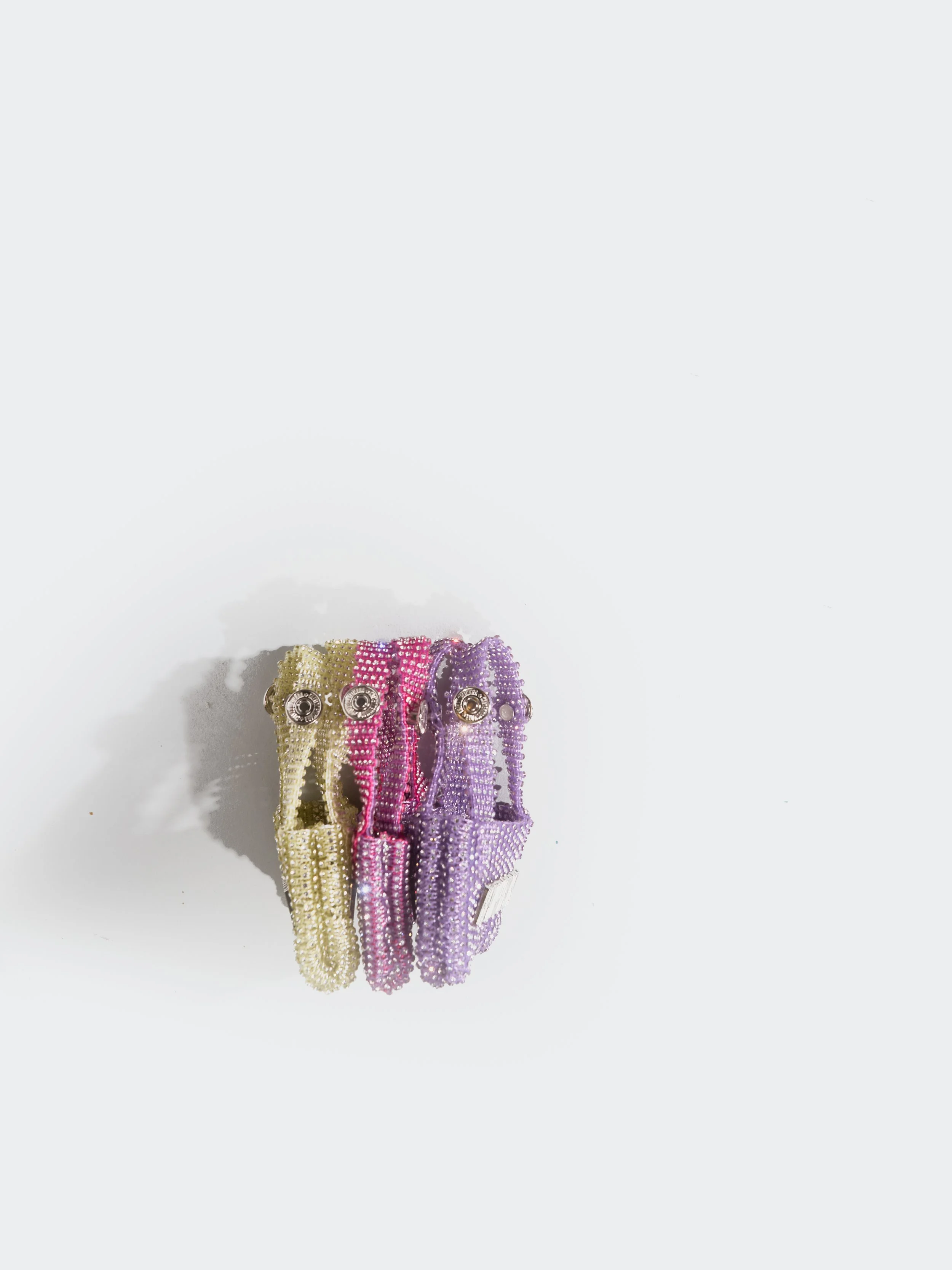 Three colorful crystal mini bags aligned on a white background.