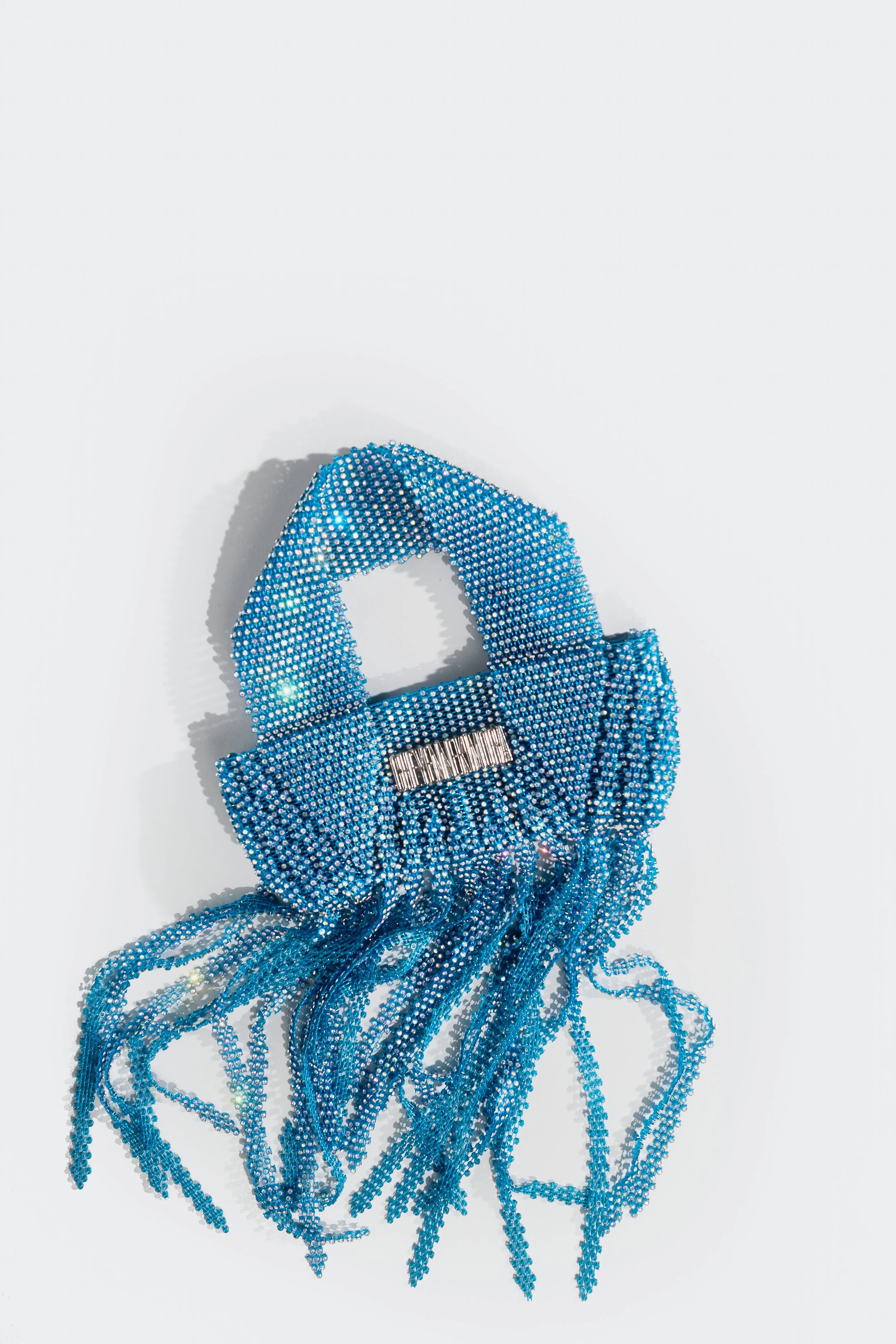 Blue crystal adorned handbag with fringe design on a white background.
