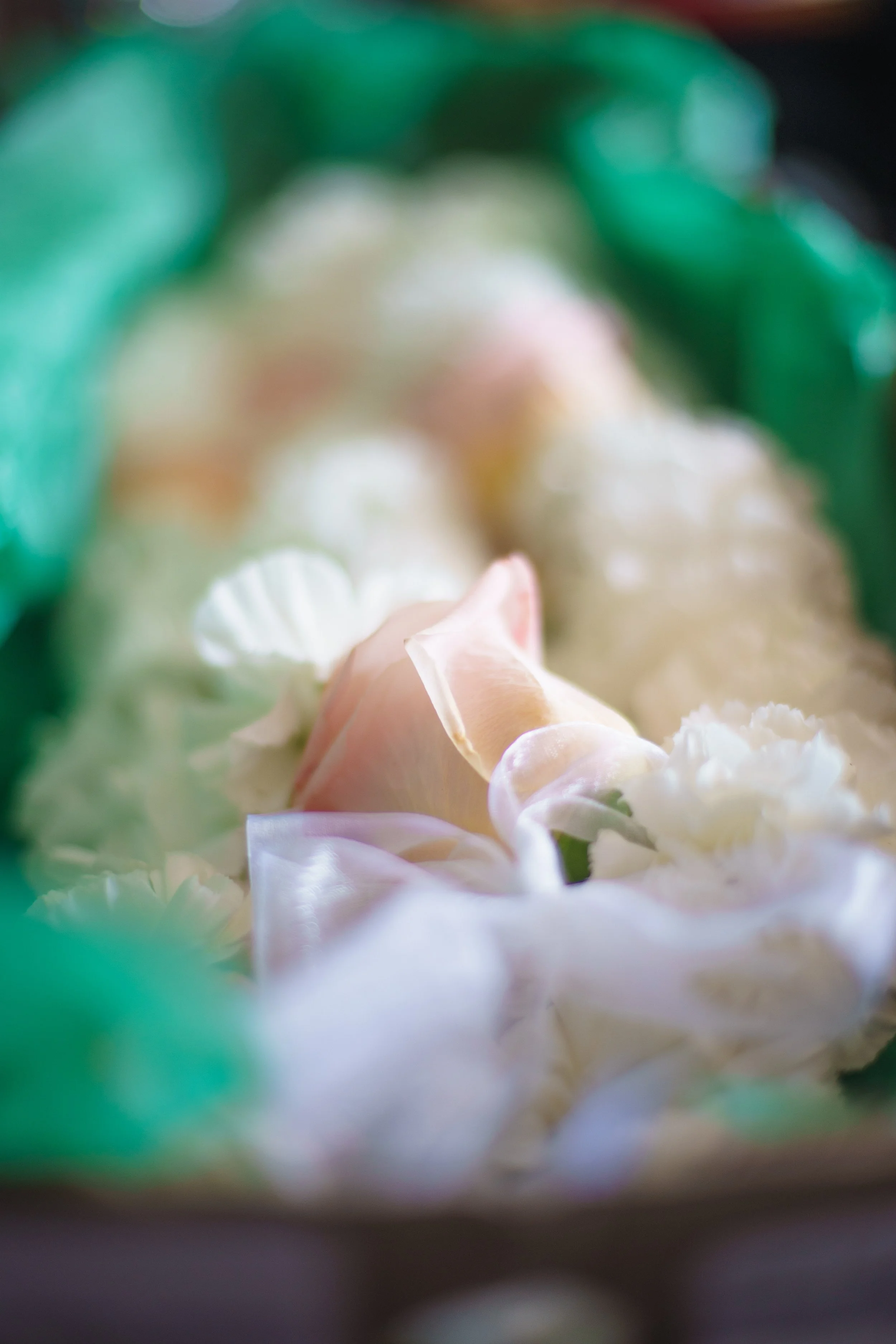 Close-up of a bouquet of cream and pink flowers with green leaves and ribbons.