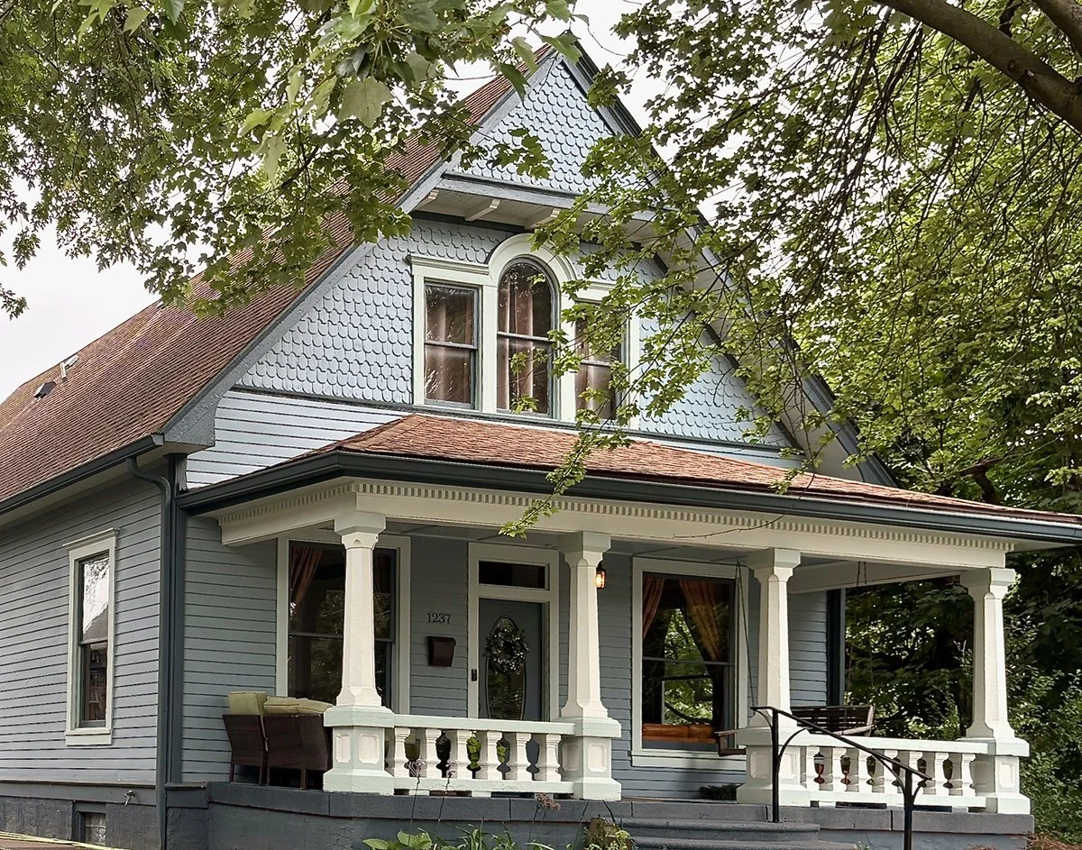 Front angle of craftsman style house with blue body and trim in green and white