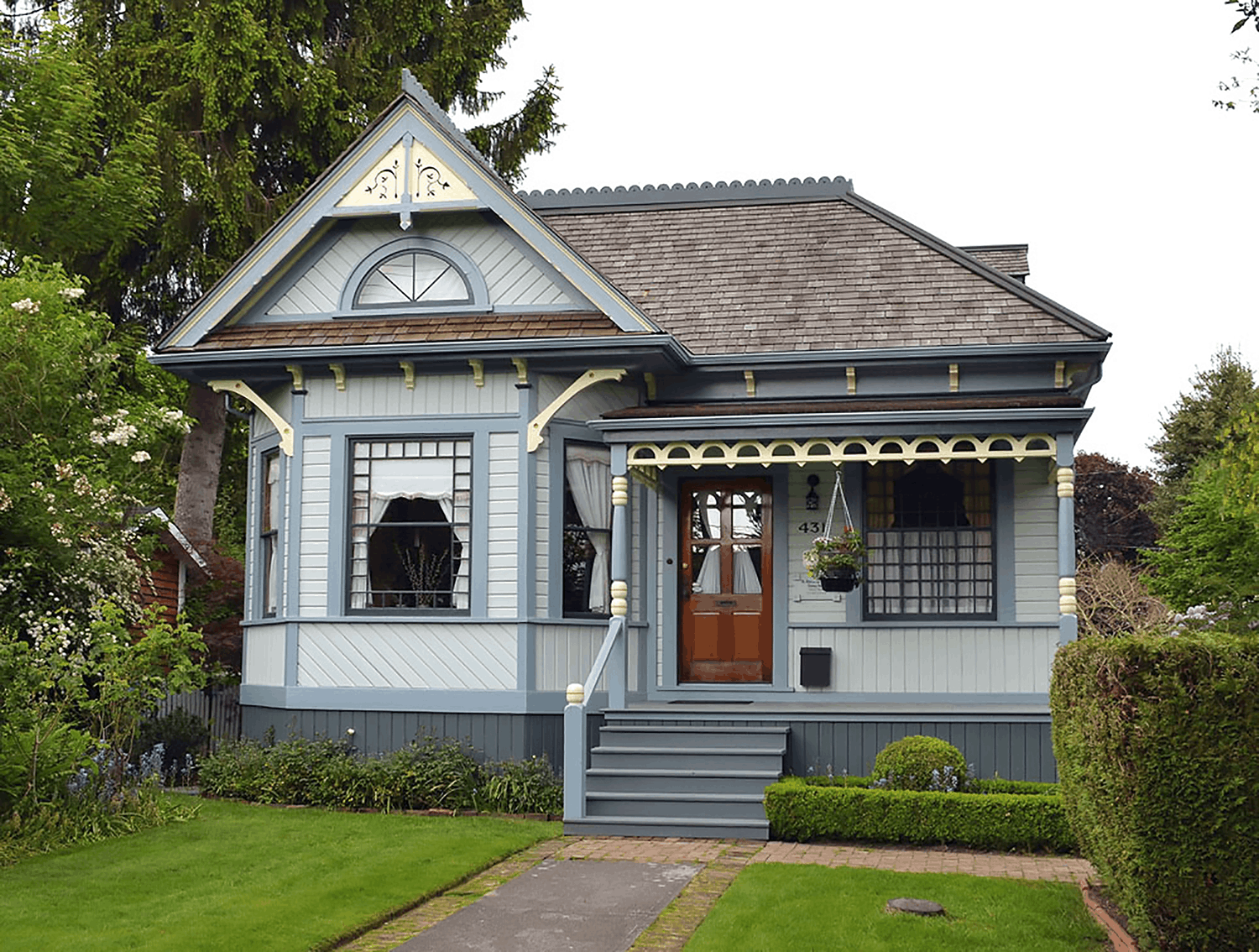 Queen Anne style heritage house painted in blue with yellow trim and dark window sash