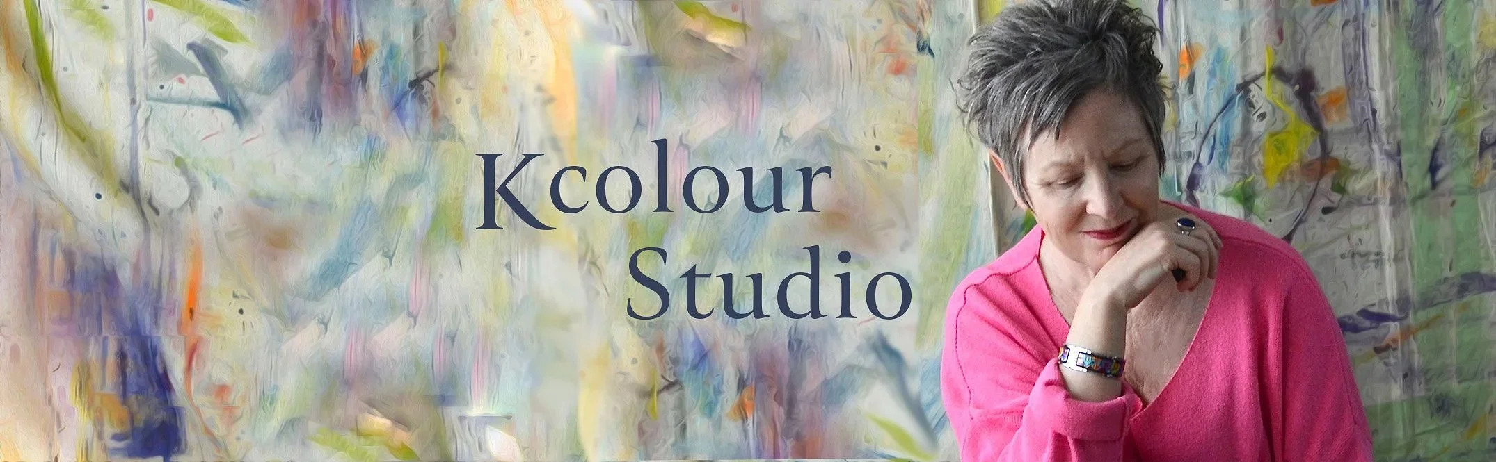Woman wearing pink sweater with chin on hand looking down with colourful painted backdrop