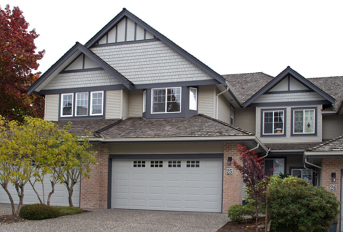 Contemporary townhouse with gabled roof and garage at front with brick accents