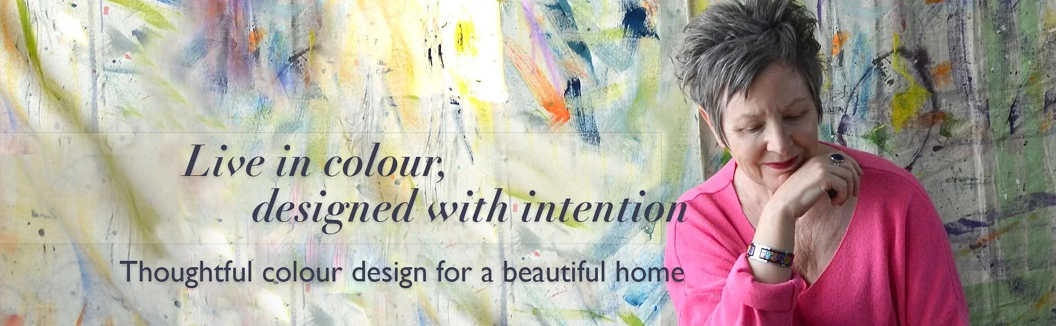 Woman wearing pink sweater with chin on back of hand, colorful painted background