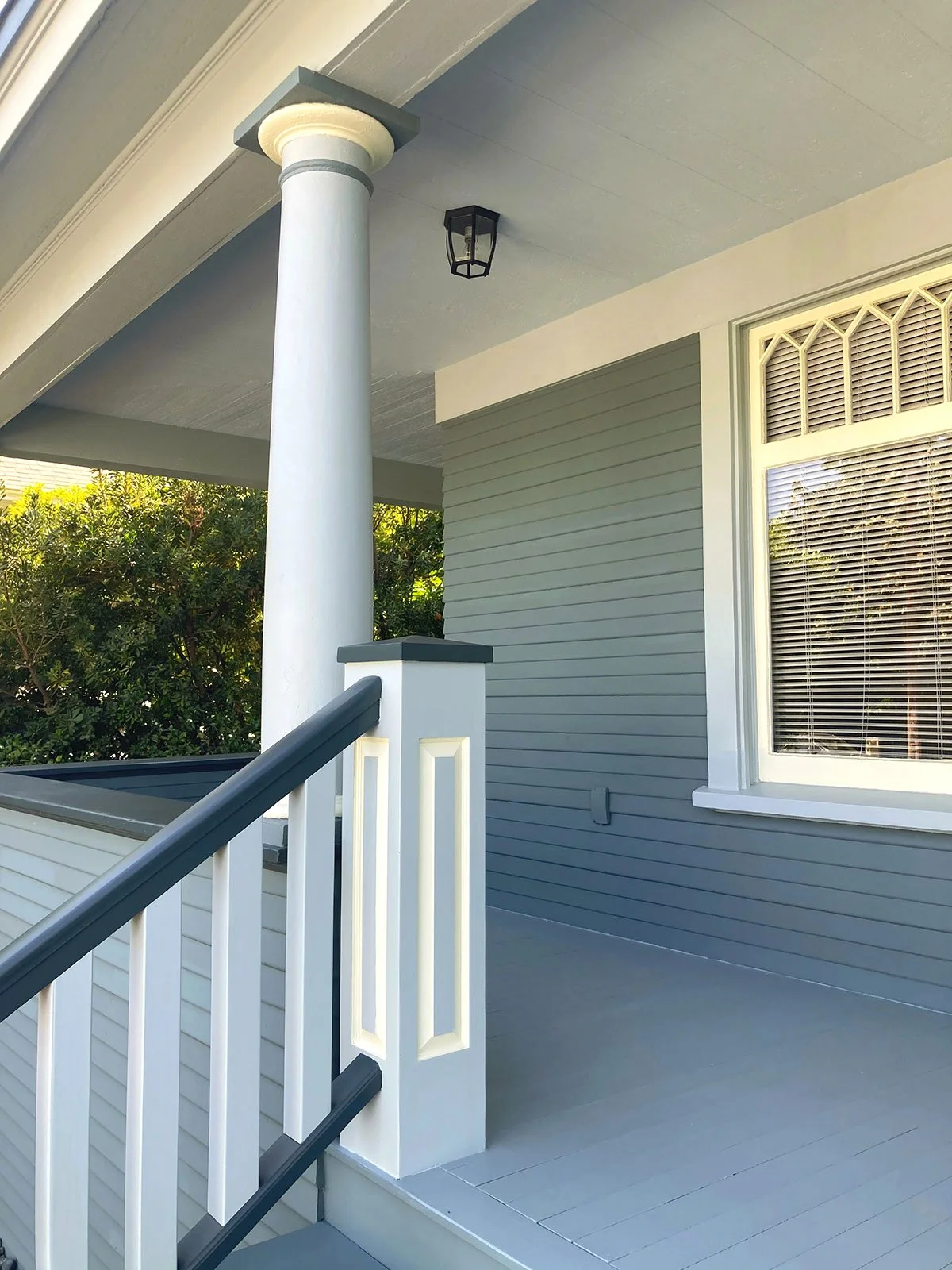 Detail of stairs and front porch post on 1900's bungalow painted in dark green and yellow
