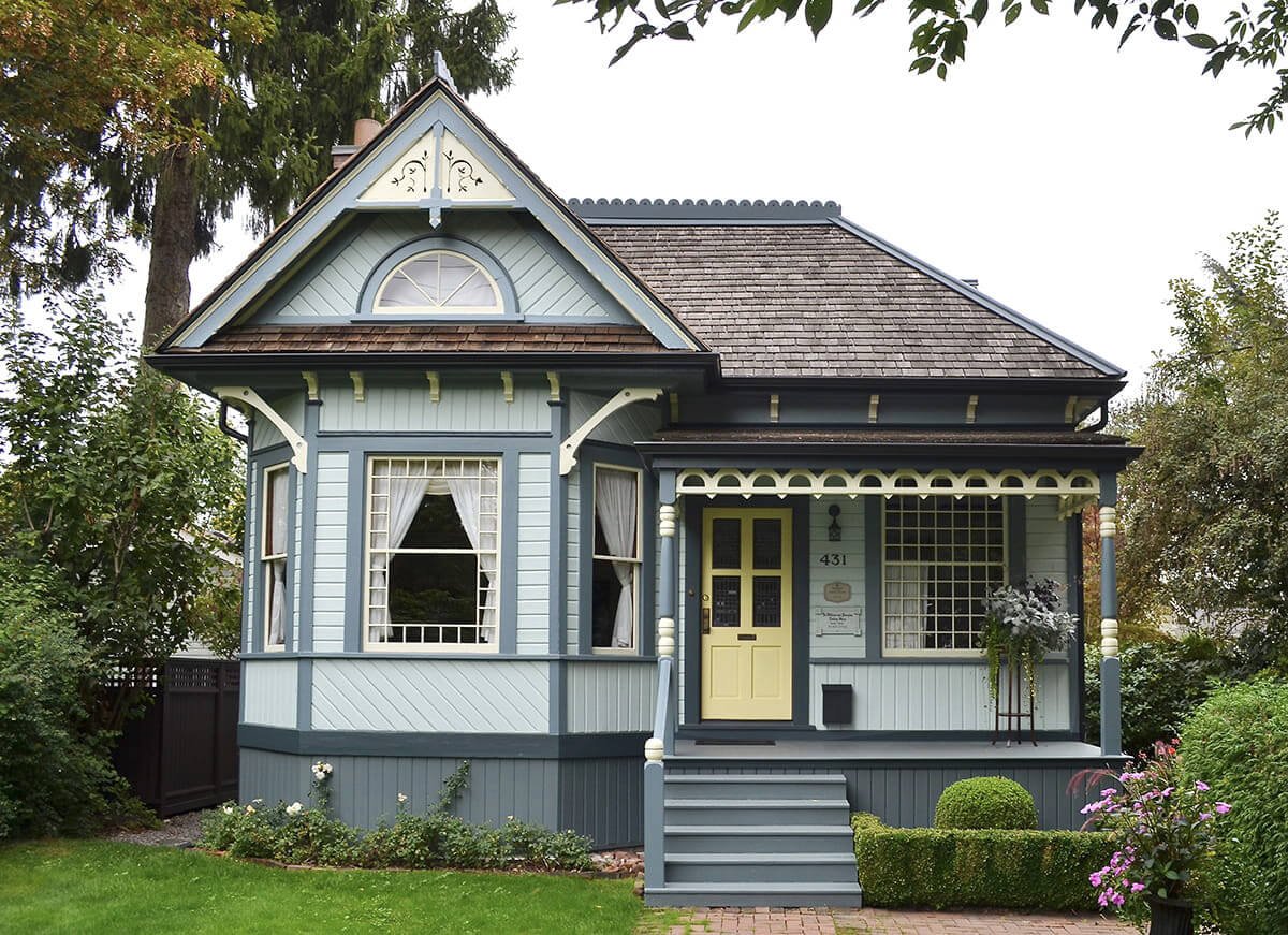 Front exterior of heritage house in the Queen Anne style painted light blue with yellow and dark blue trim