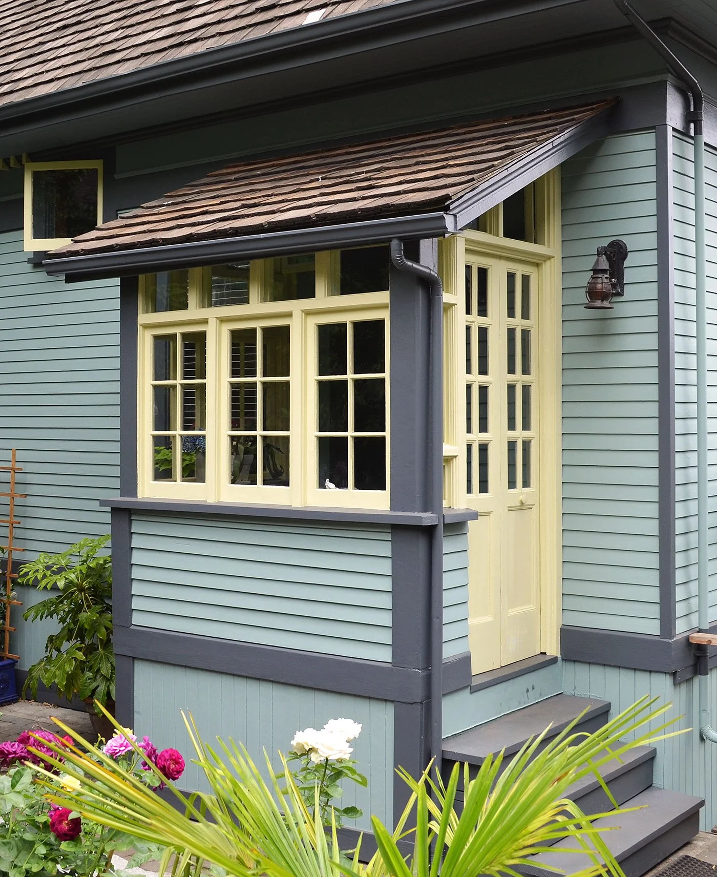 Built-in side porch to Edwardian heritage house with yellow door and windows and siding in soft blue