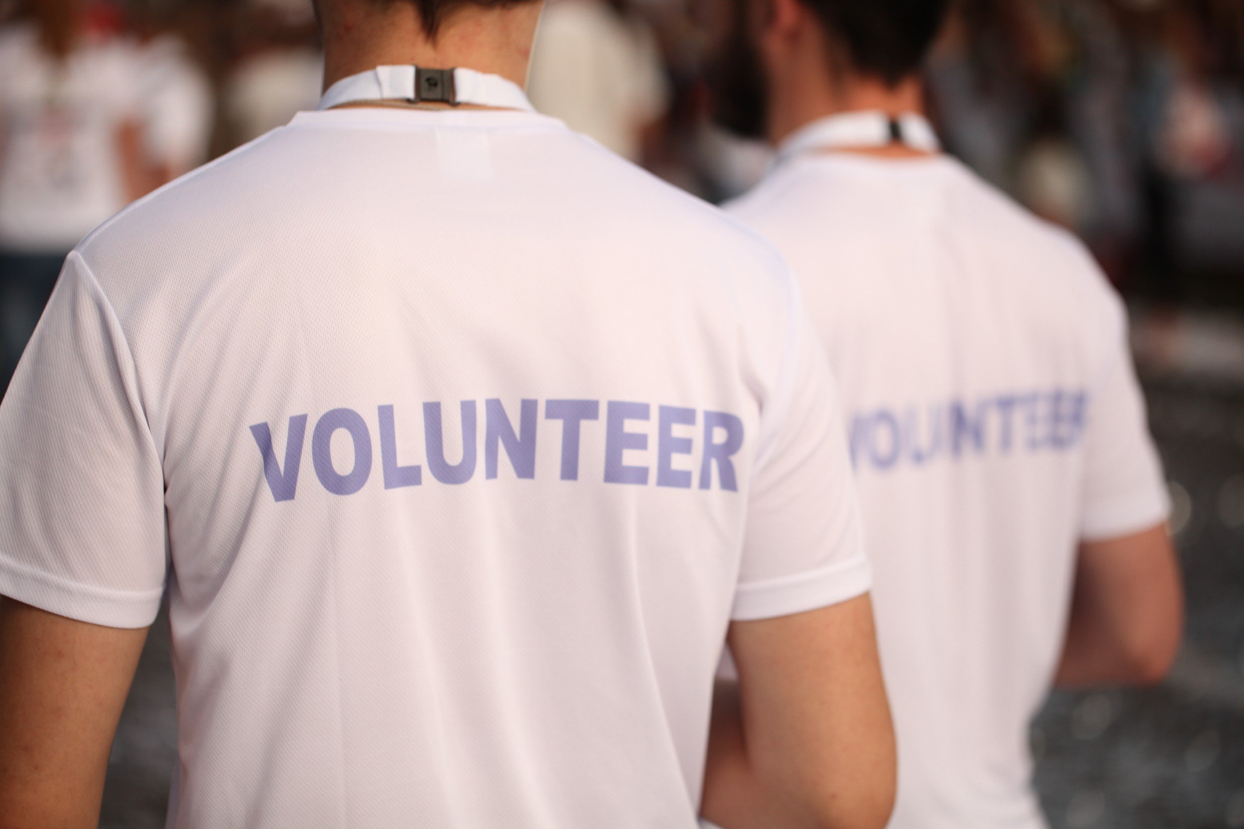 Photo of two people wearing t-shirts labeled "VOLUNTEER" on the back