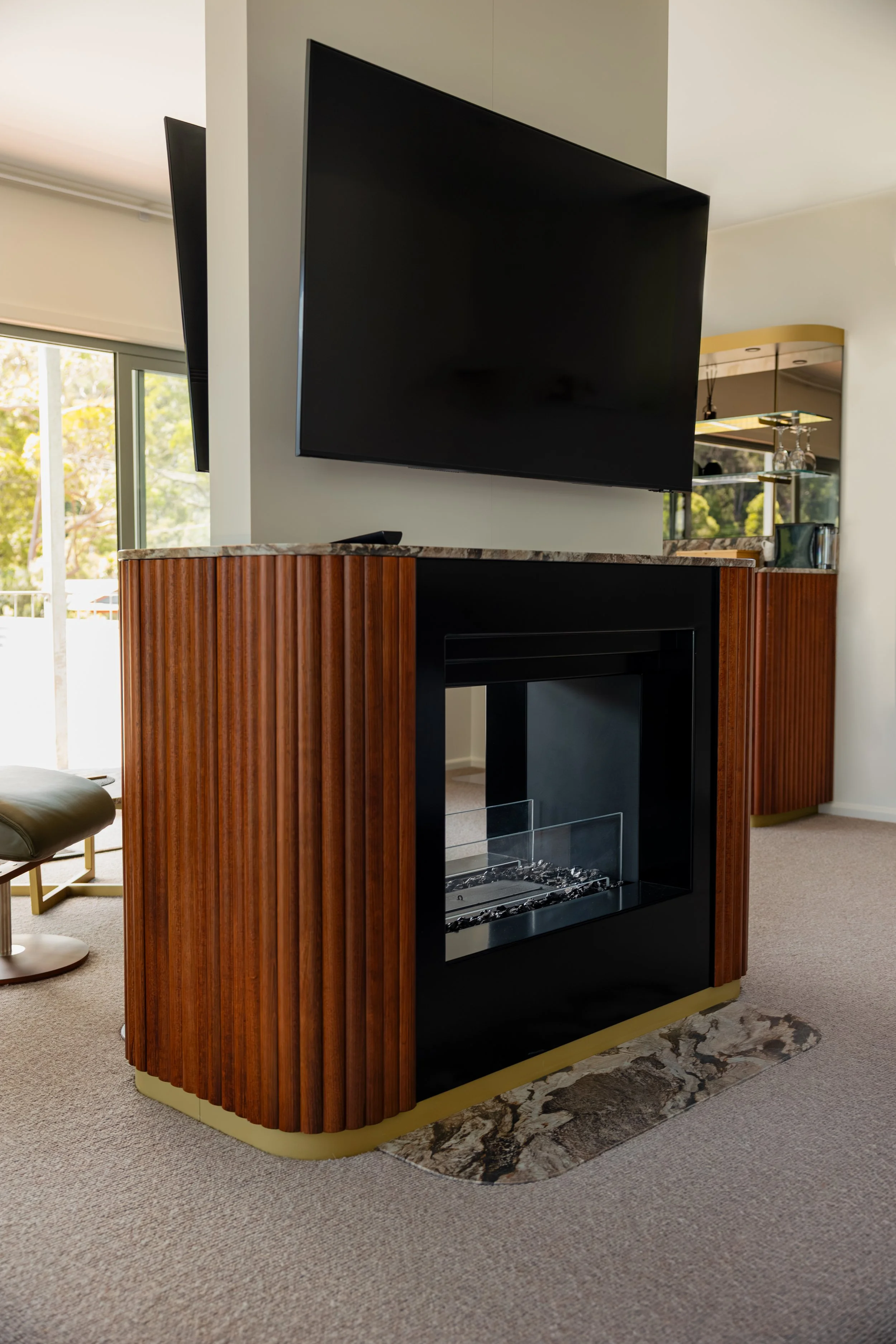 Living room with a modern fireplace, wooden paneling, and a mounted flat-screen TV.
