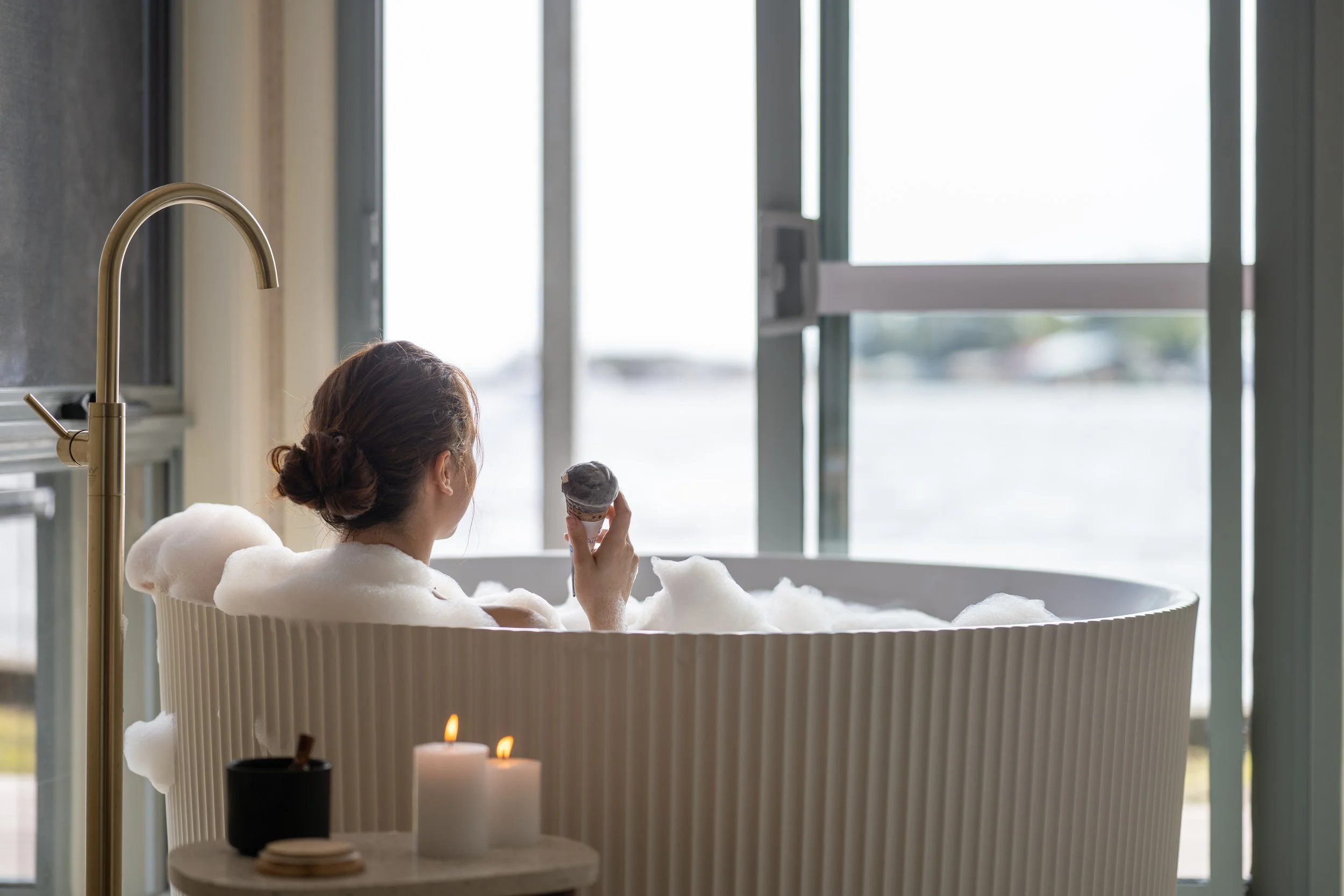 Maugean Suites - Lady deep soaking in the oversized fluted bath with sliding door open, mere meters from the harbour's edge.jpg