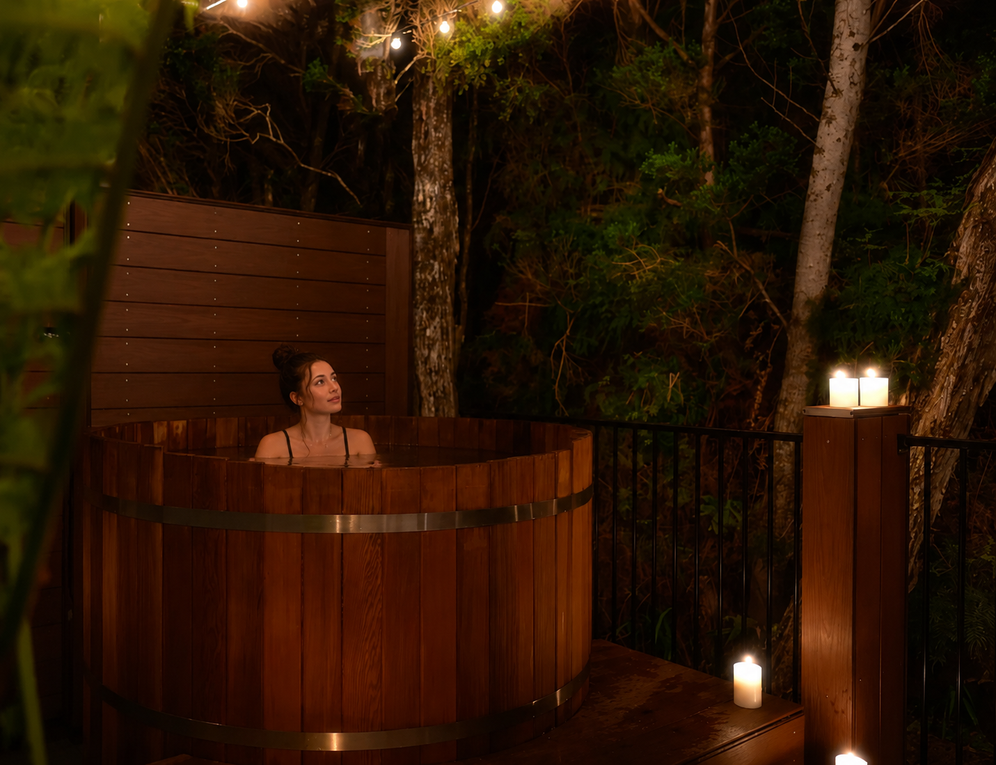 A lady soaks in a cedar hot tub, looking up at the stars above