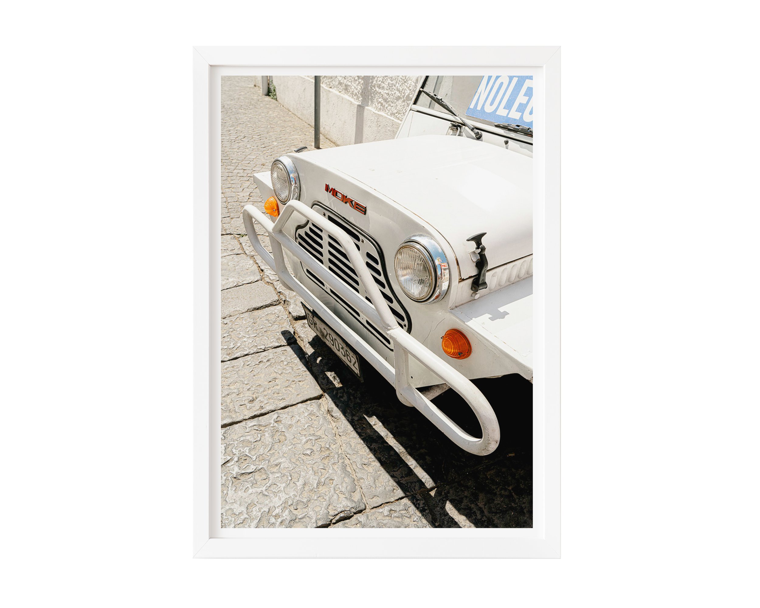Close-up of vintage white Moke car parked on sunlit cobblestone street in Southern Europe, captured in golden daylight – retro travel photography print by Nicole Toland