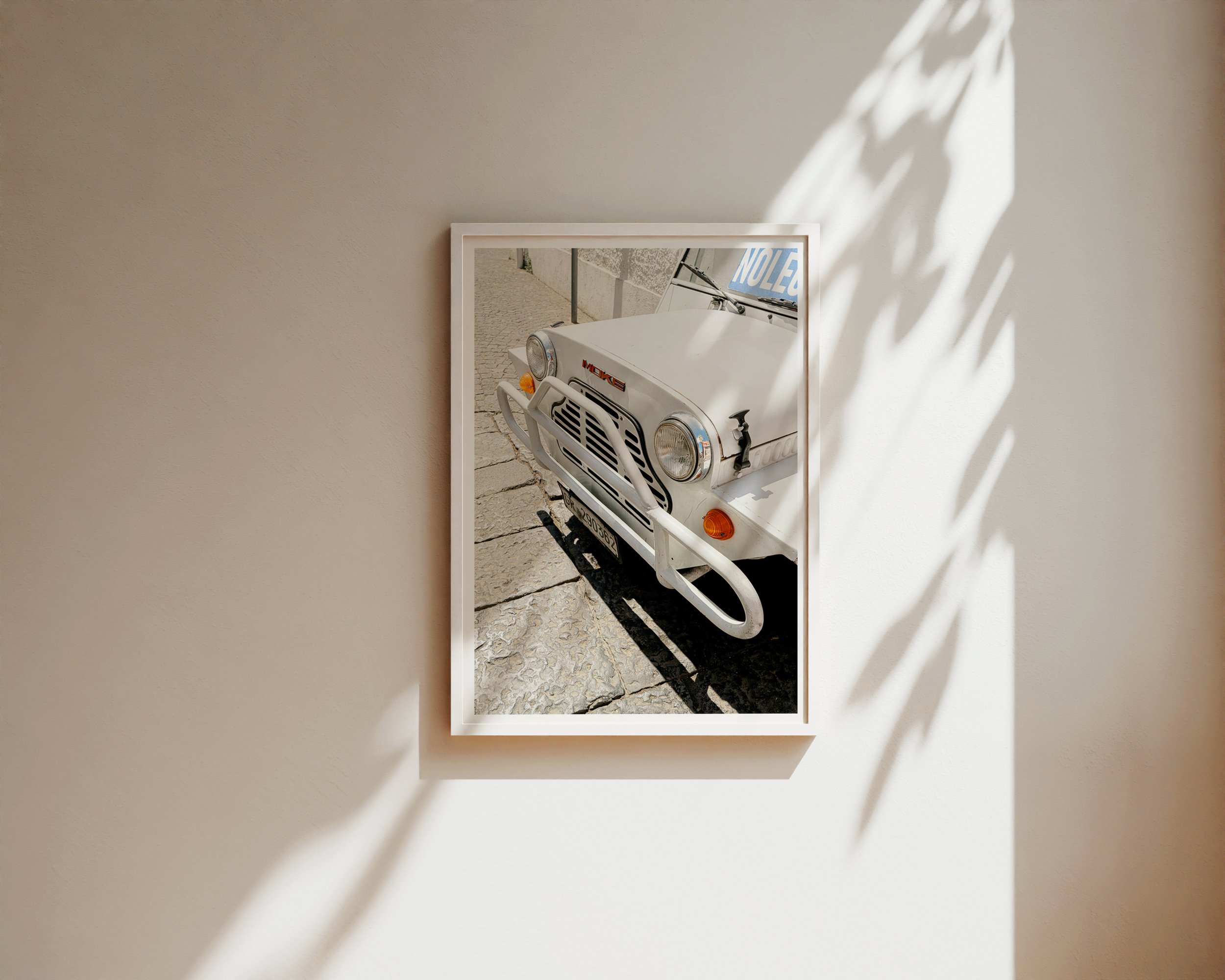 Close-up of vintage white Moke car parked on sunlit cobblestone street in Southern Europe, captured in golden daylight – retro travel photography print by Nicole Toland