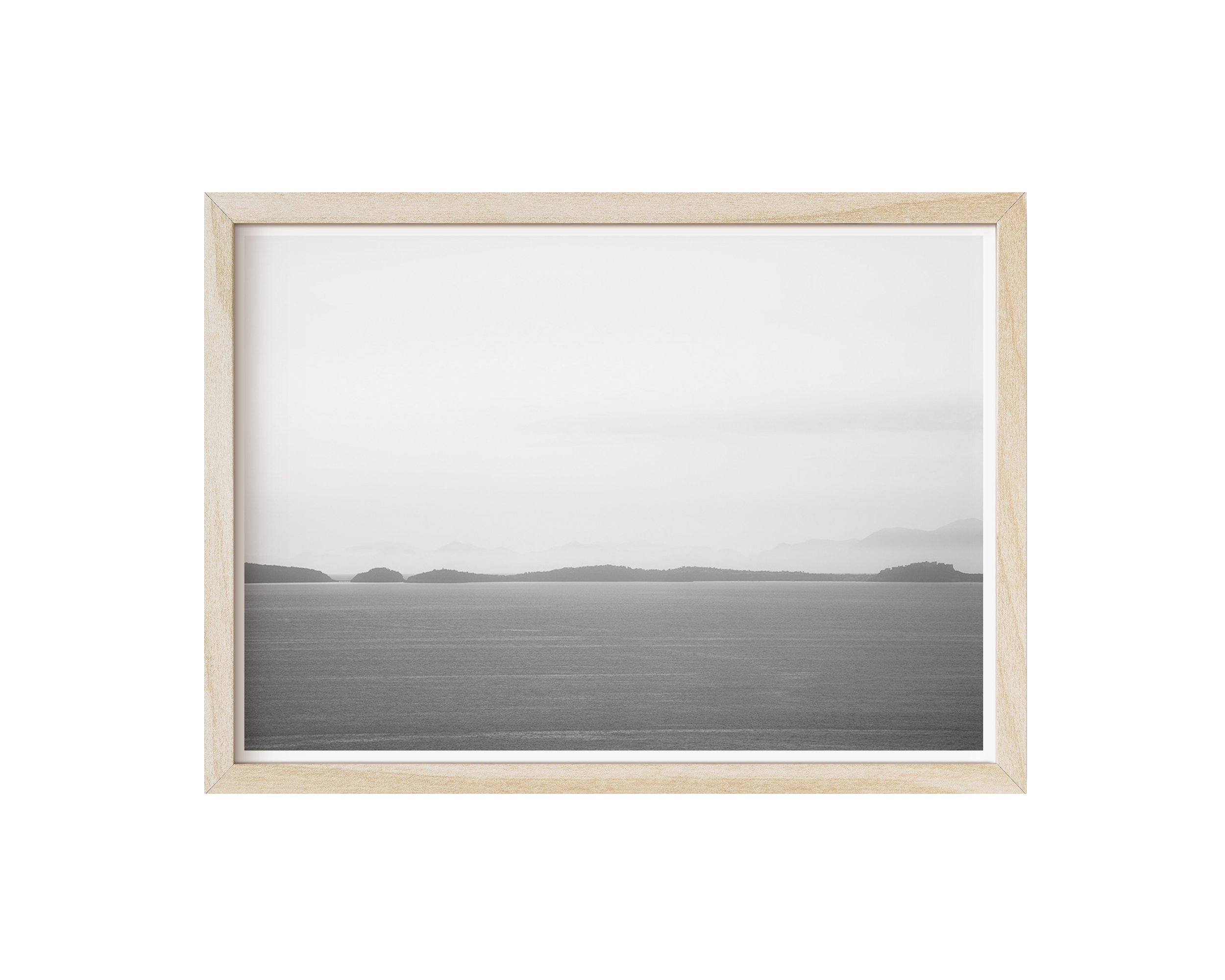A tranquil black and white fine art photograph capturing a calm sea and misty distant islands beneath a soft, tonal sky.