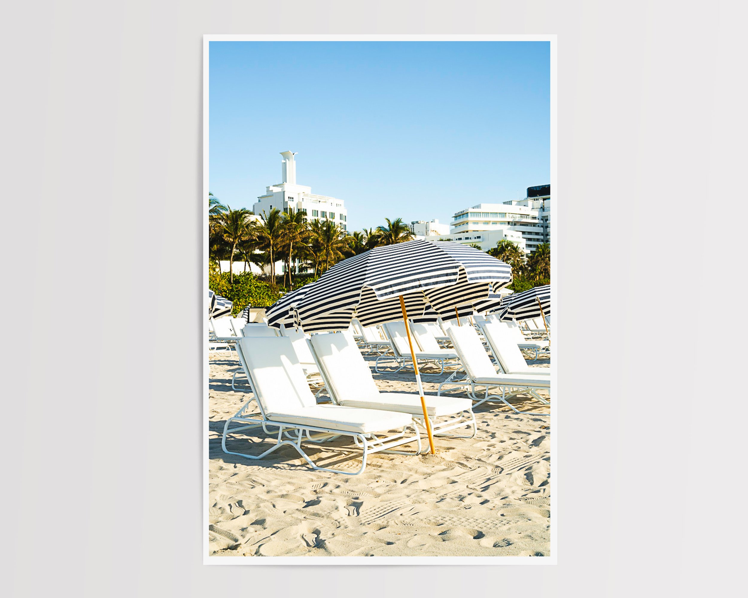 This minimalist beach scene captures architectural repetition and tranquil resort vibes, perfect for modern decor, coastal interiors, or photography collectors seeking serene, geometric compositions.