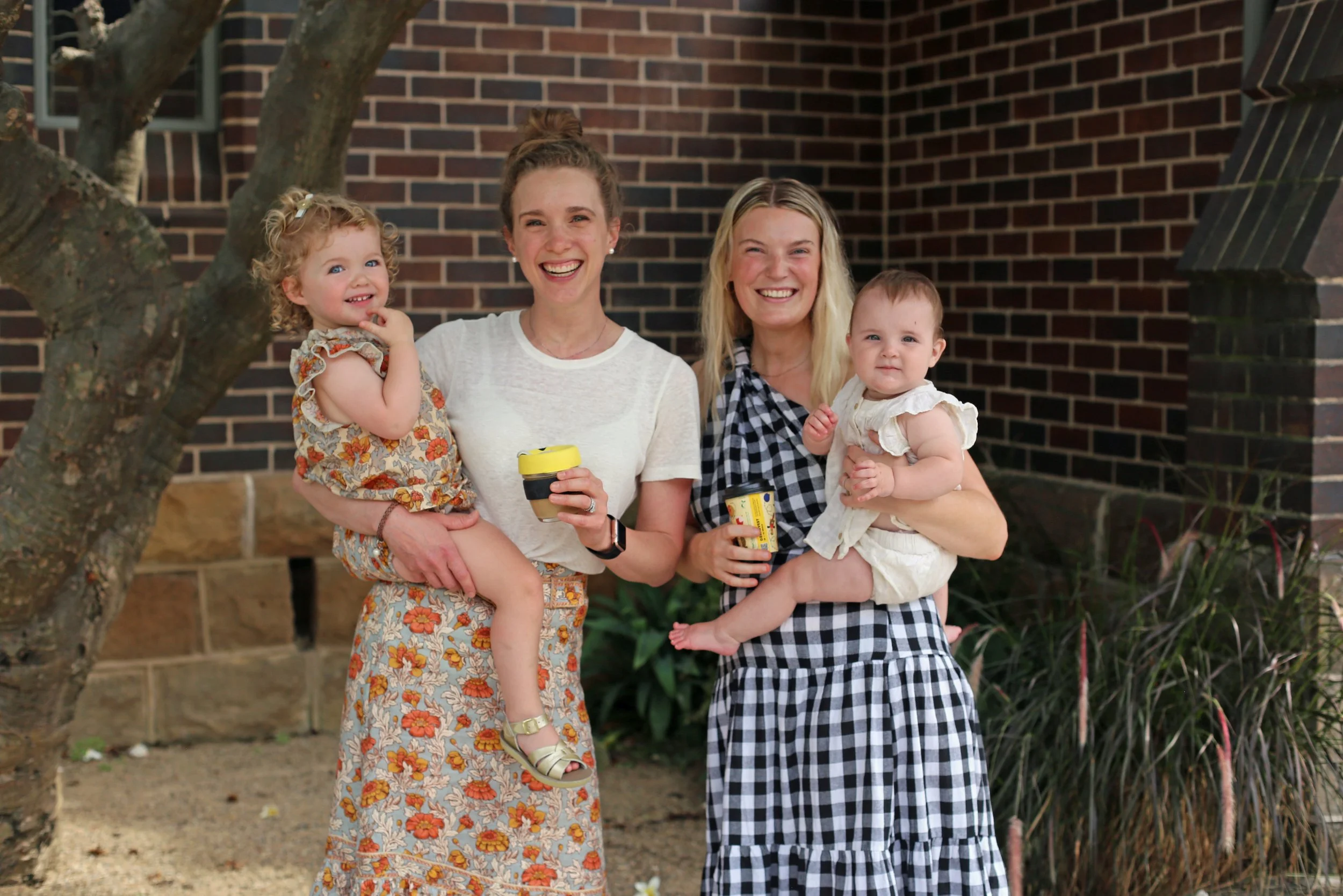 Two young women holding their kids.
