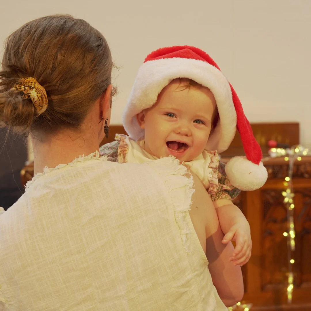 A smiling baby wearing a Christmas hat.