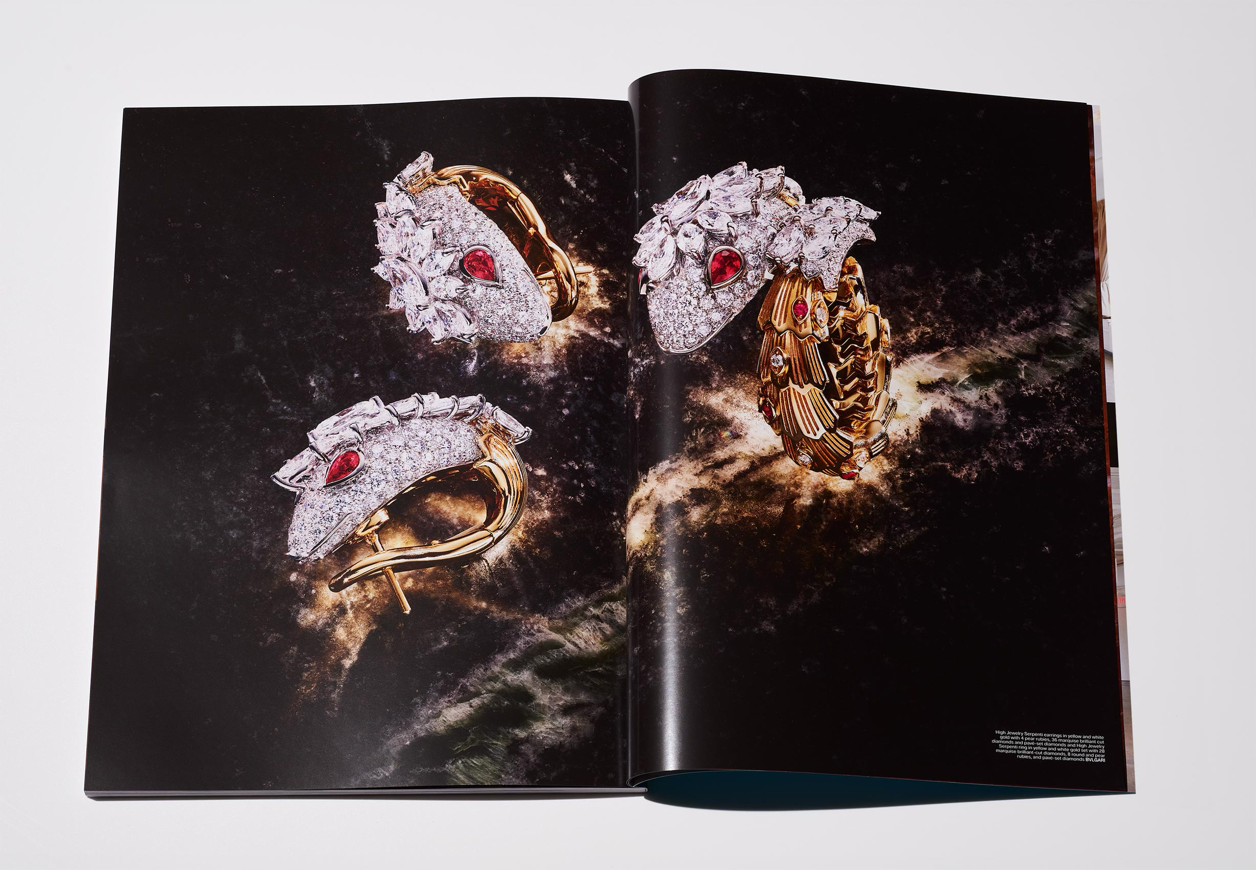 Open magazine spread featuring jewelry, including diamond and ruby rings and earrings, set against a dark, cosmic background.