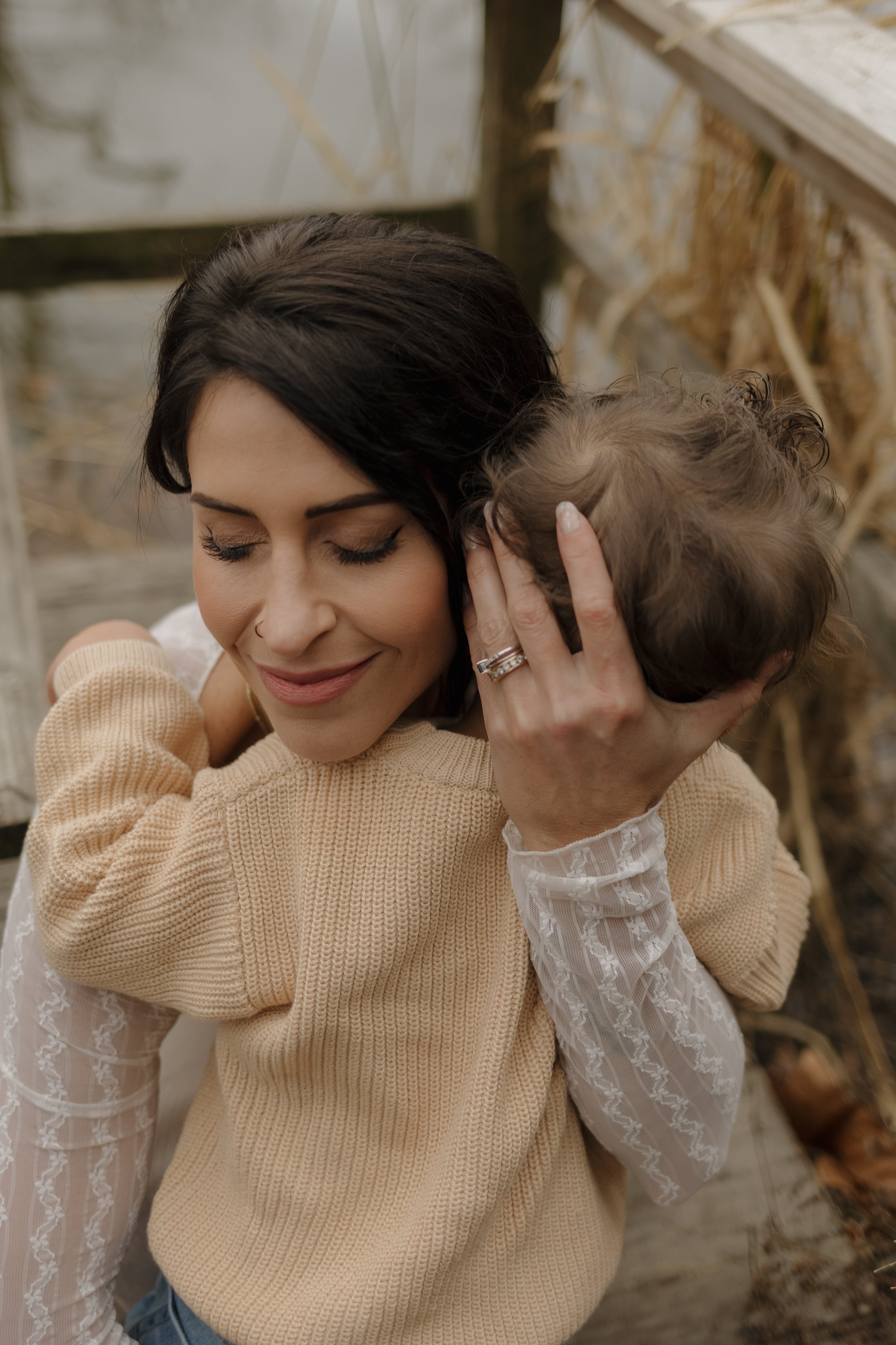 A woman hugging a small dog outdoors with her eyes closed and a peaceful expression.