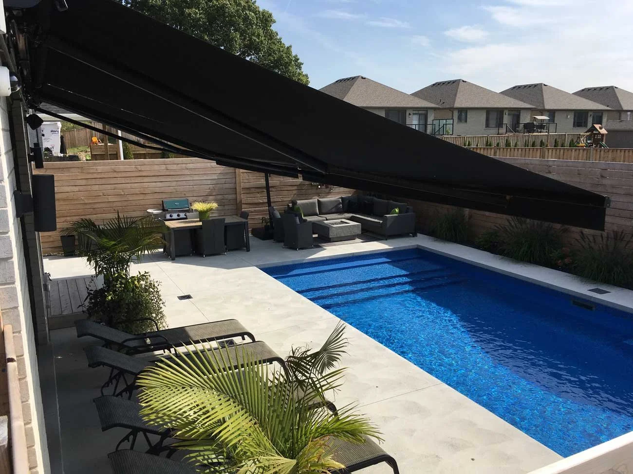 Retractable awning extended over a pool deck in London, Ontario during summer