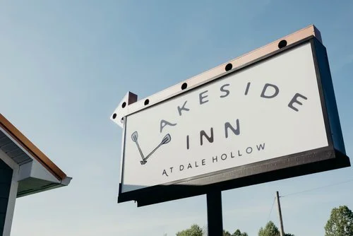 Low angle view of the modern, minimalist Lakeside Inn At Dale Hollow black property sign against a clear blue sky.